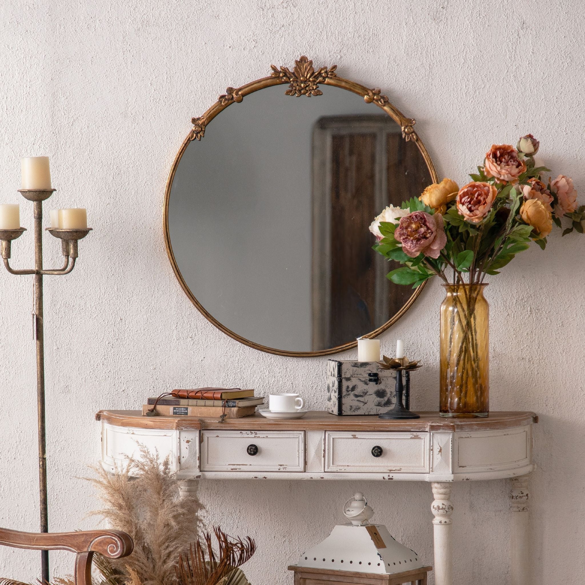 Serena round wall mirror in antique gold with floral crest hung above a demilune console
