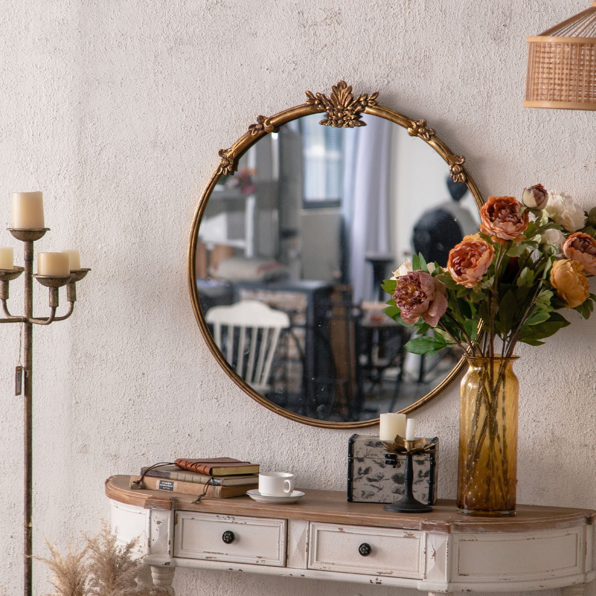 Serena antique gold round mirror styled on a textured white wall with peonies and candelabra