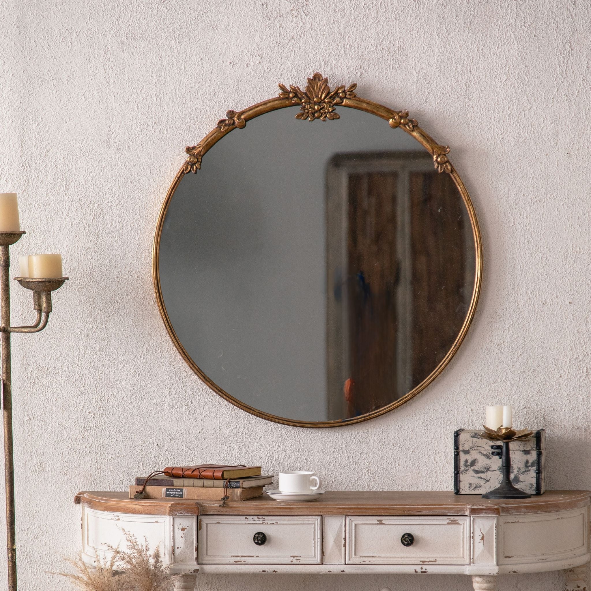 Serena round gold mirror above a console styled with books and dried stems