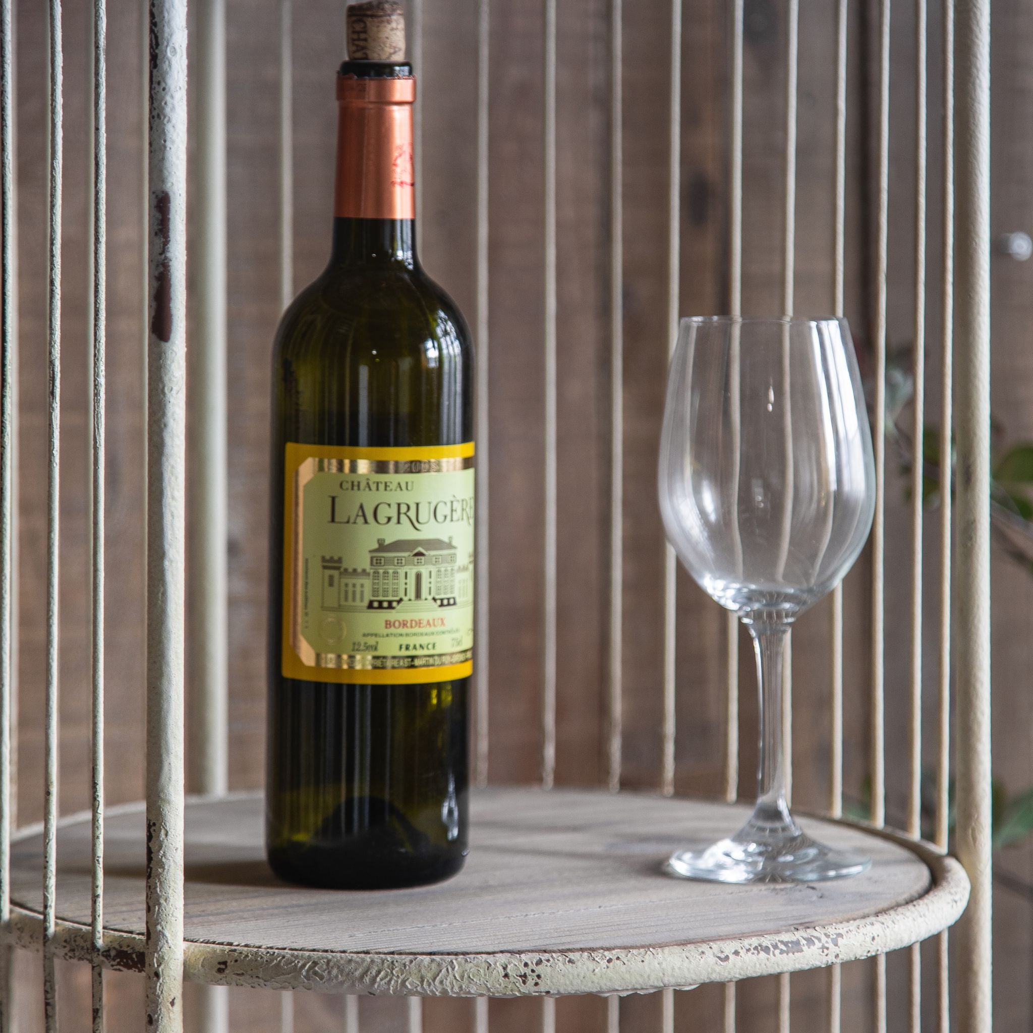 Brindisi birdcage shelf styled against a timber wall with baskets and greenery
