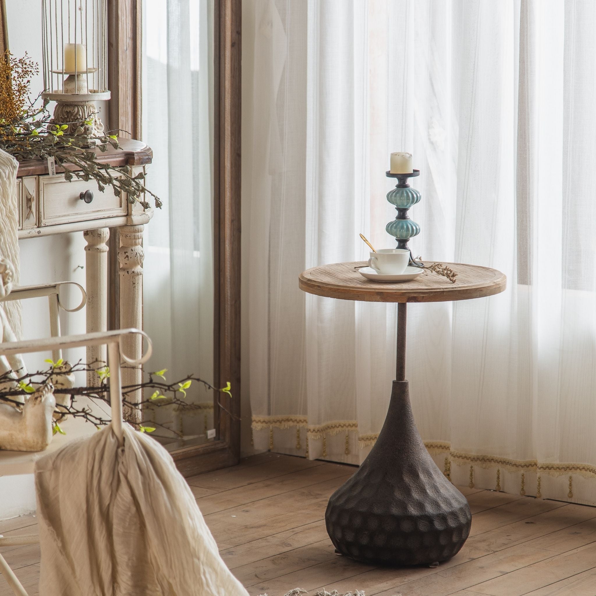 Vanna tall side table styled beside a chair with cherub statue