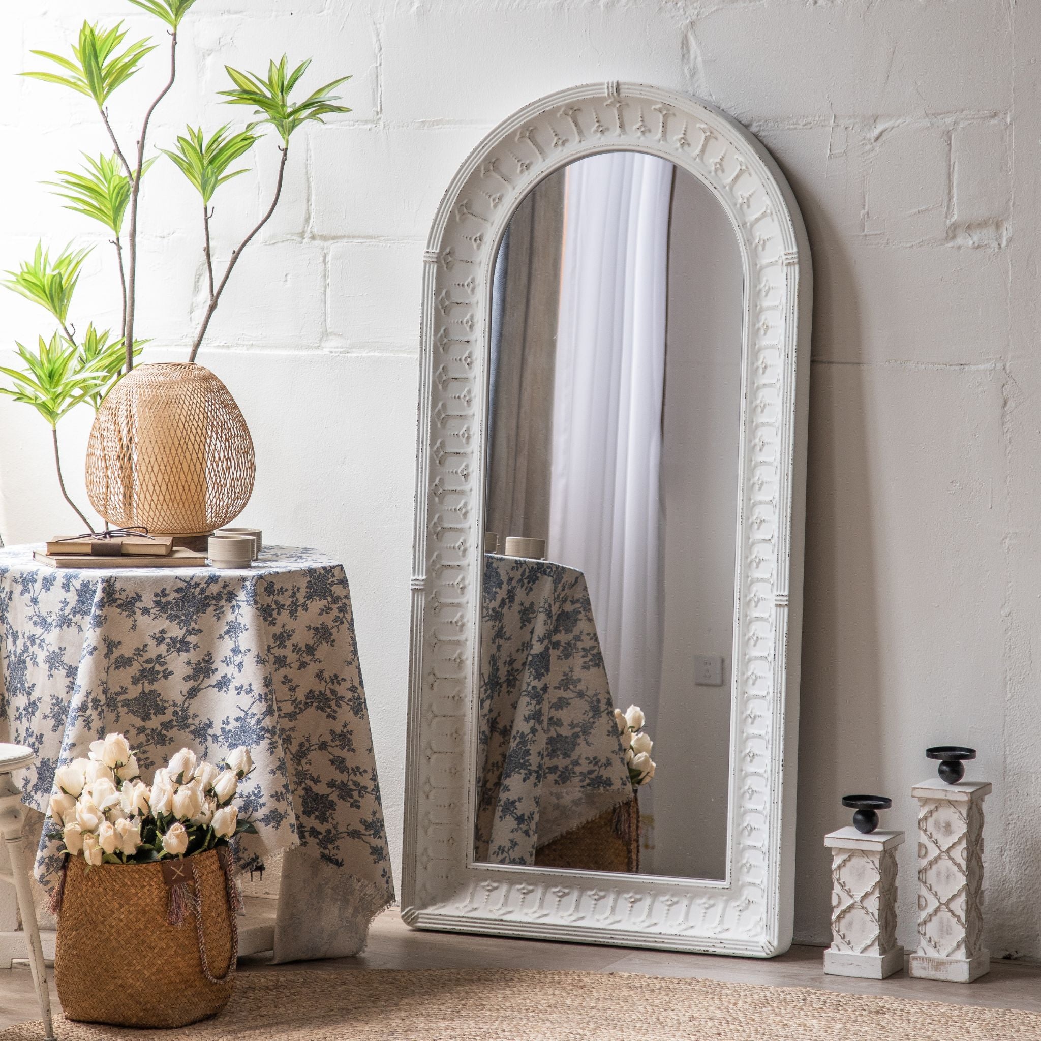 Theron arched leaner mirror in white with embossed frame leaning against a wall
