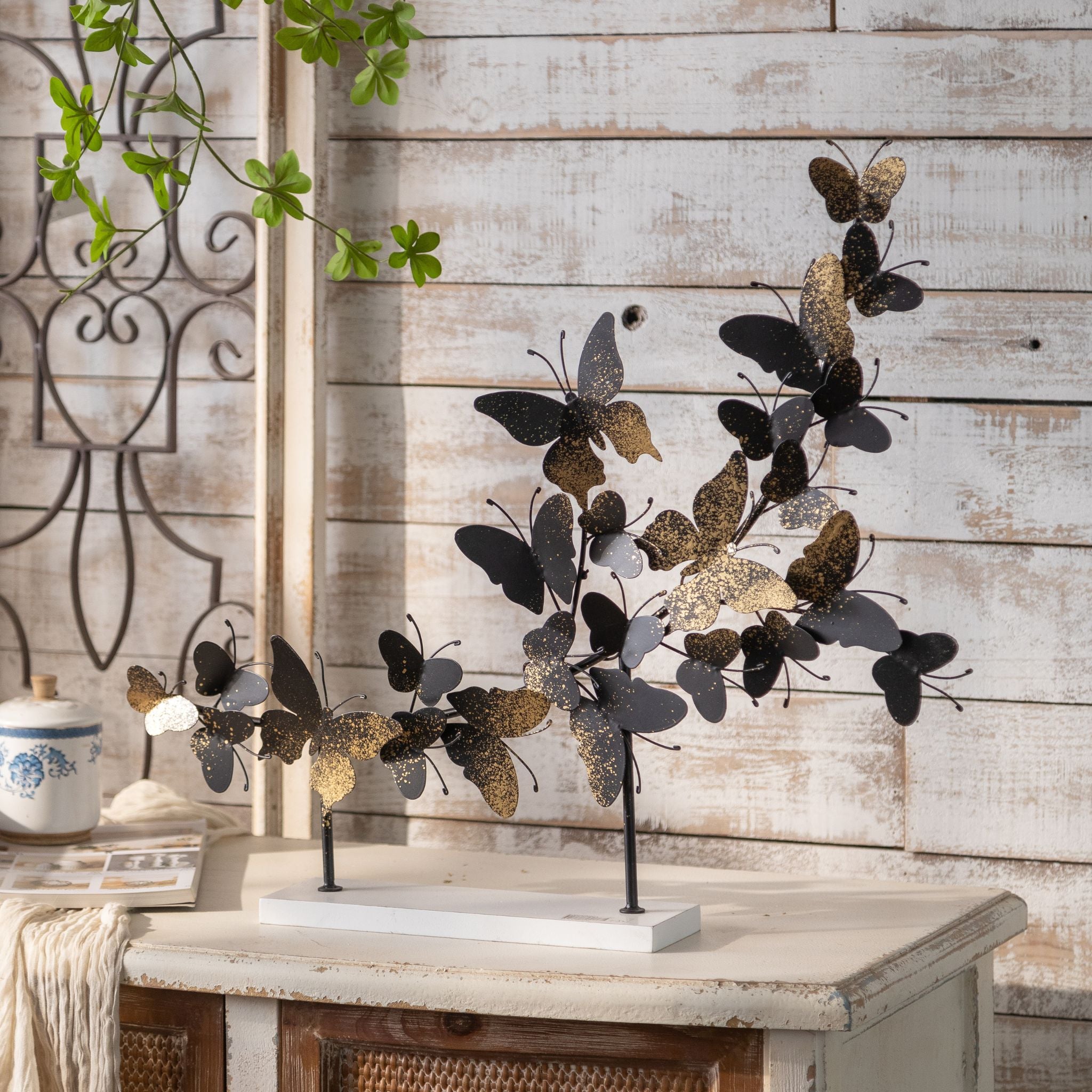 Tessa butterfly sculpture with black and gold speckled butterflies on a white timber base