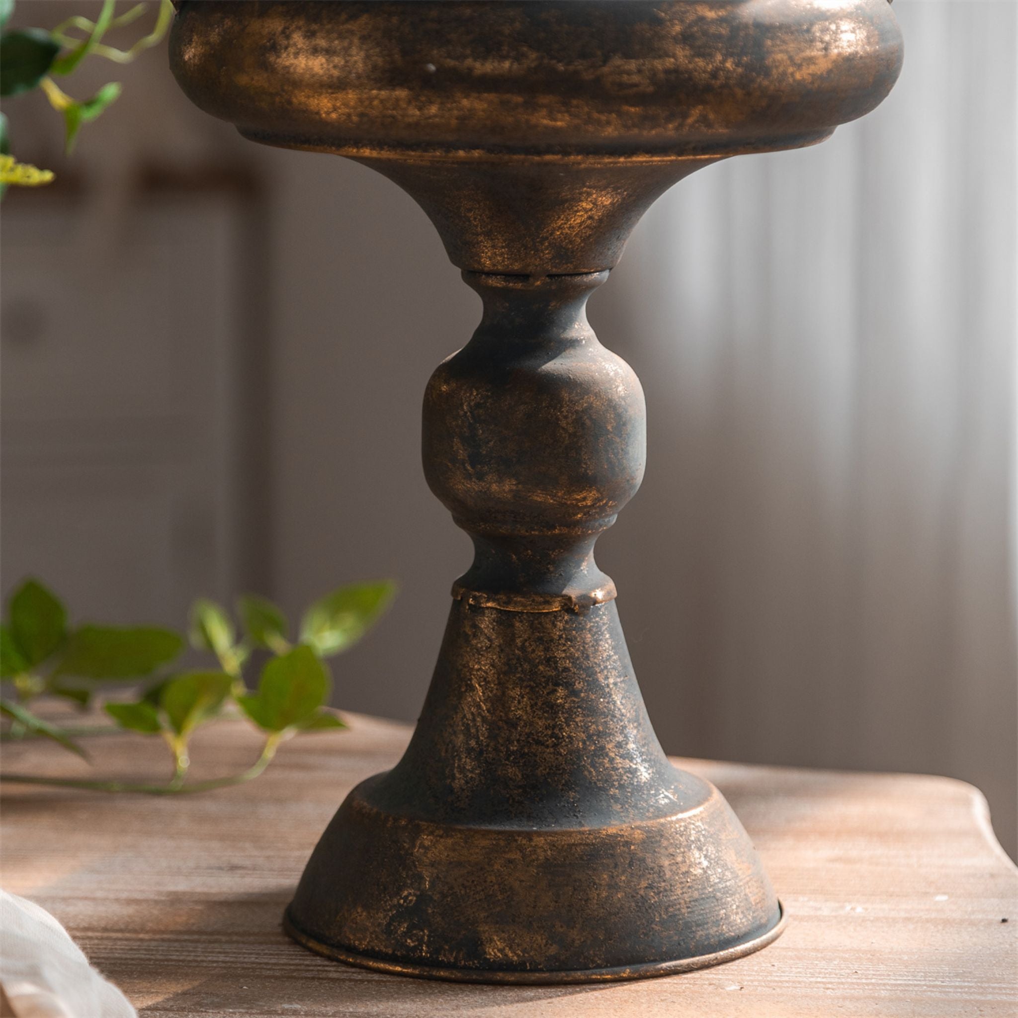 Arles bronze finish urn planter styled with greenery by a window