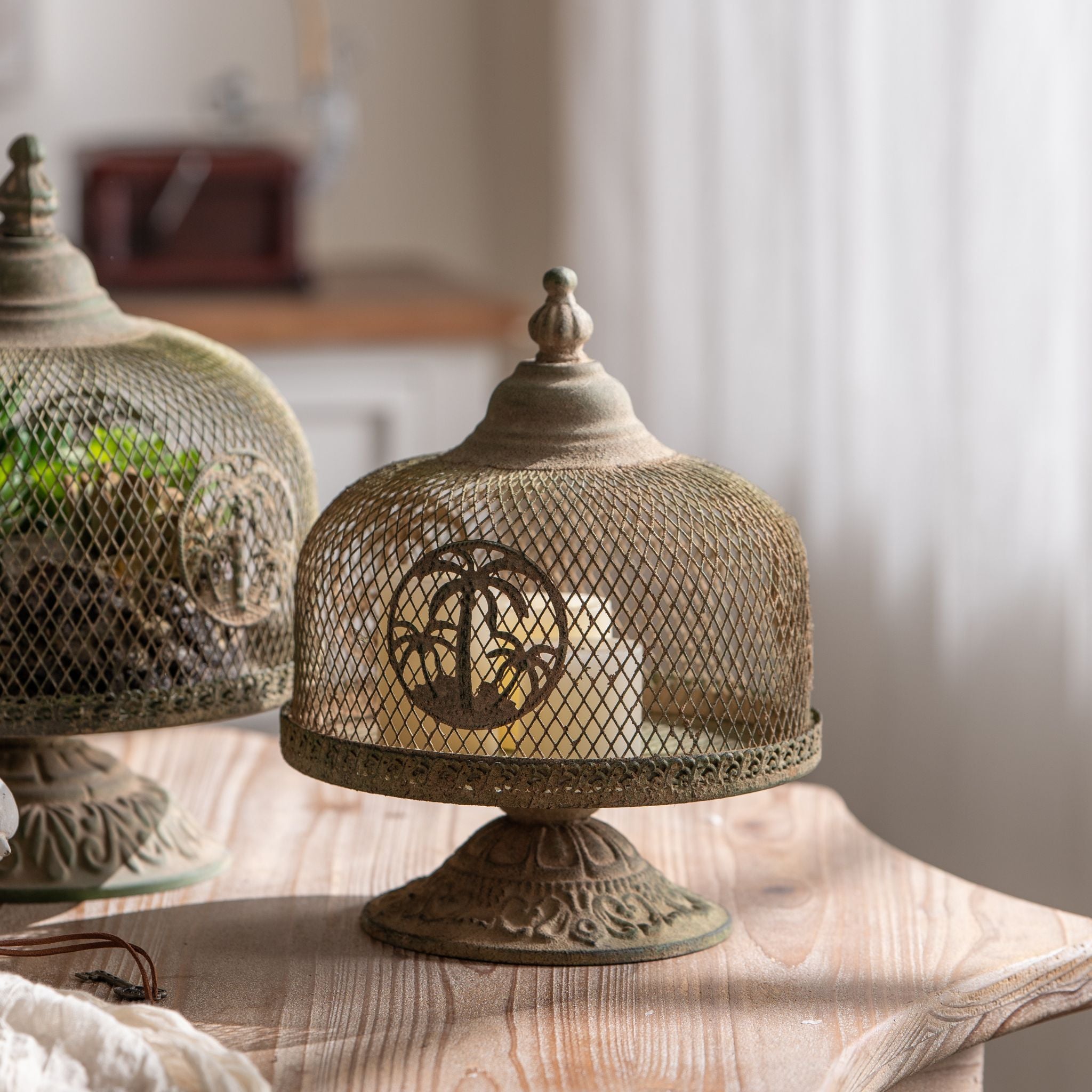 Ramona mesh cloche on pedestal base with palm medallion glowing with a candle inside