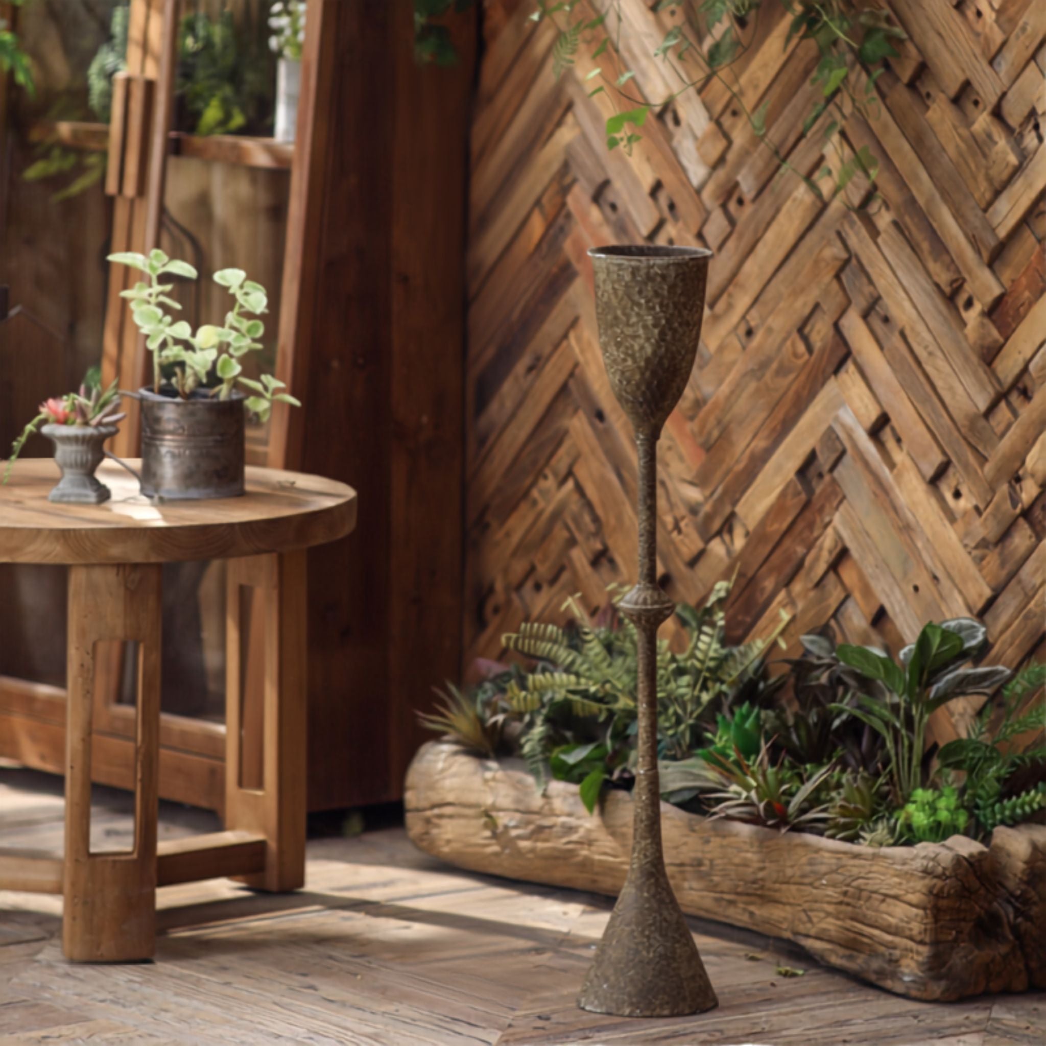 Granada goblet planter in aged iron standing beside a garden table with fern