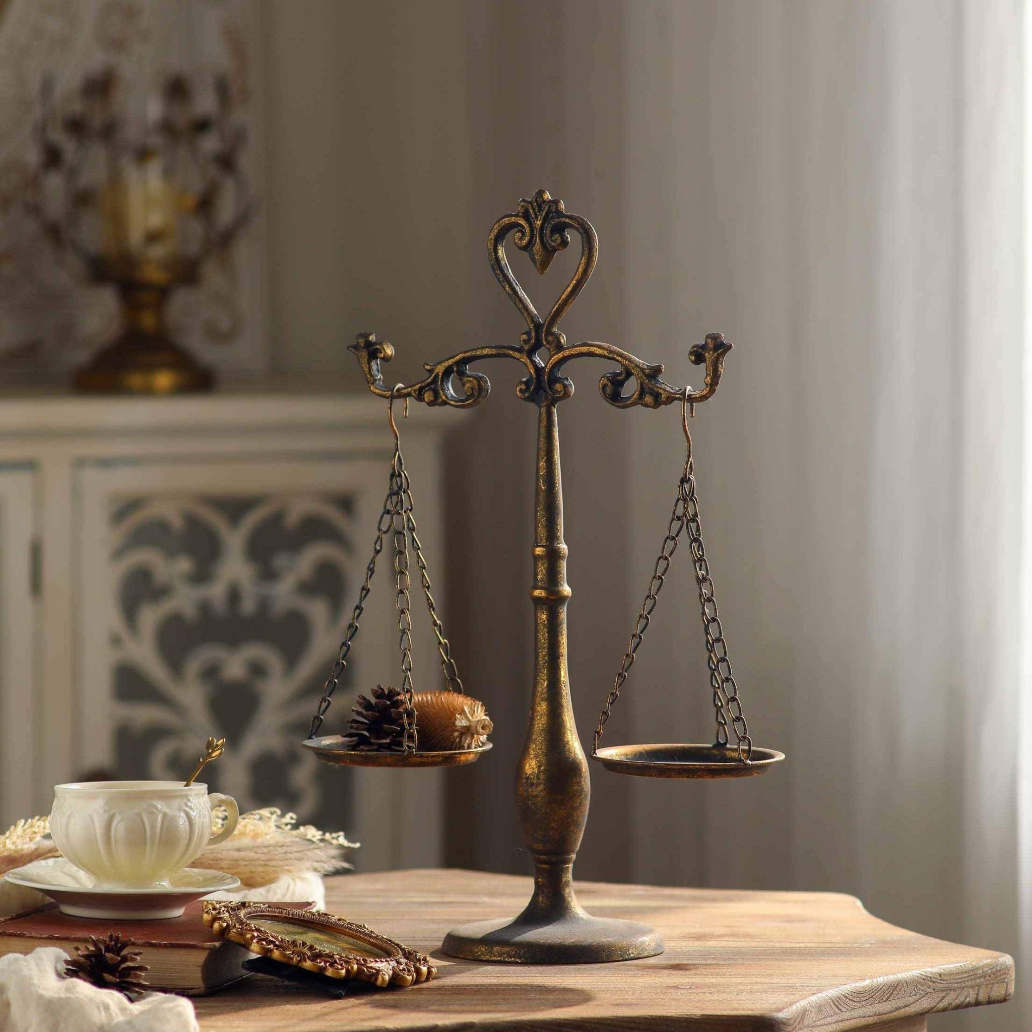 Nimes decorative balance scales in aged gold iron on a timber table with teacup