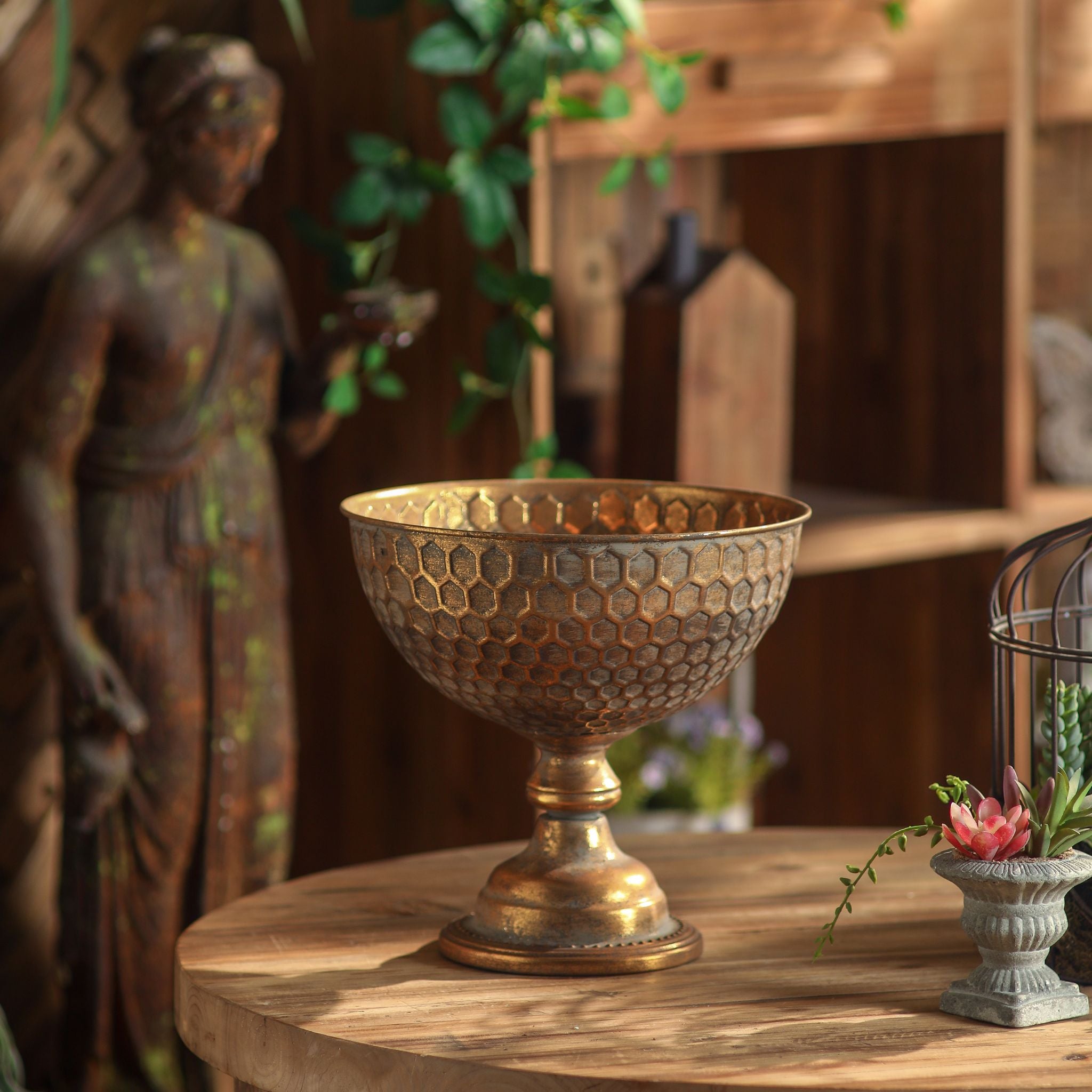 Oriana honeycomb pedestal bowl in antique gold on a round timber table
