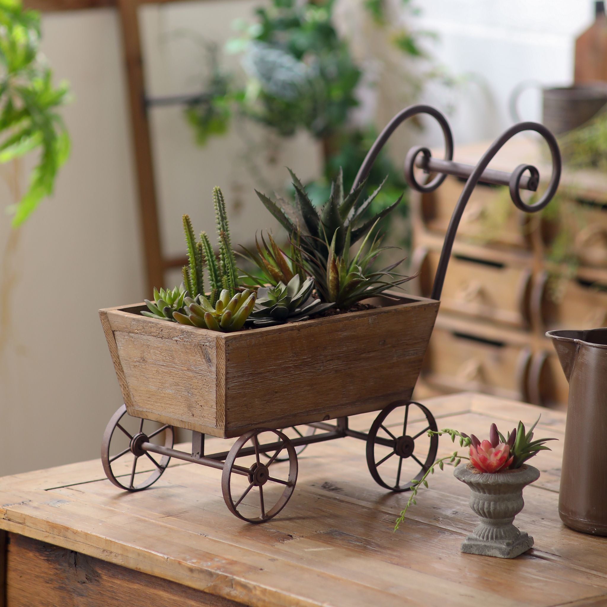 Paloma wagon planter in fir wood with iron wheels and scrolled handle on a bench