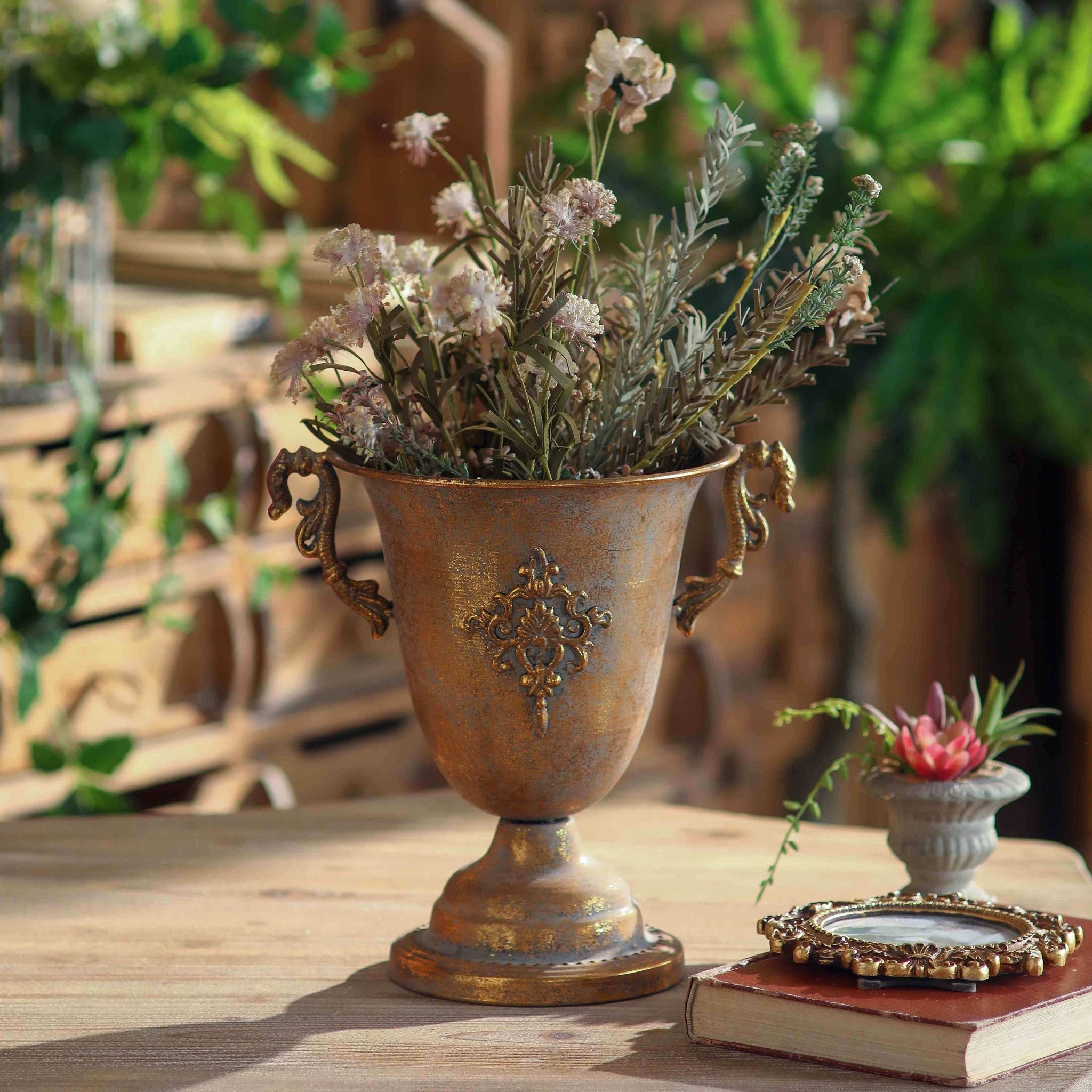 Bruno urn planter in rust and gold patina with damask emblem on a timber table