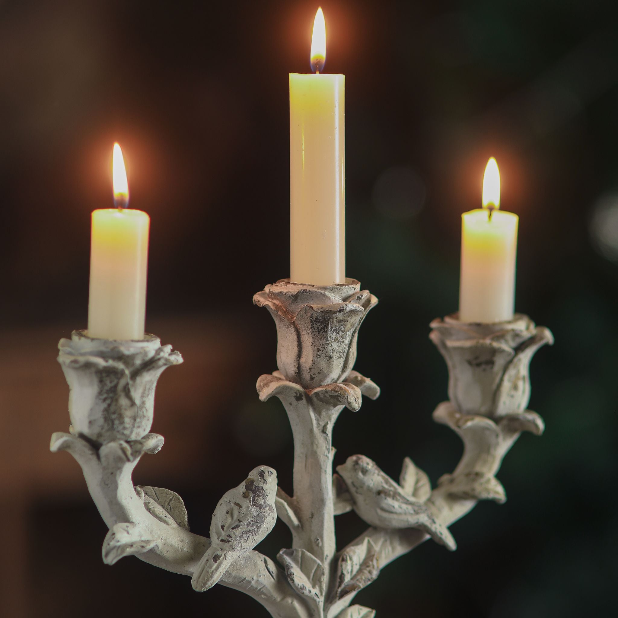 Corfu candelabra with rose cups, perched birds and ribbon bow in warm light