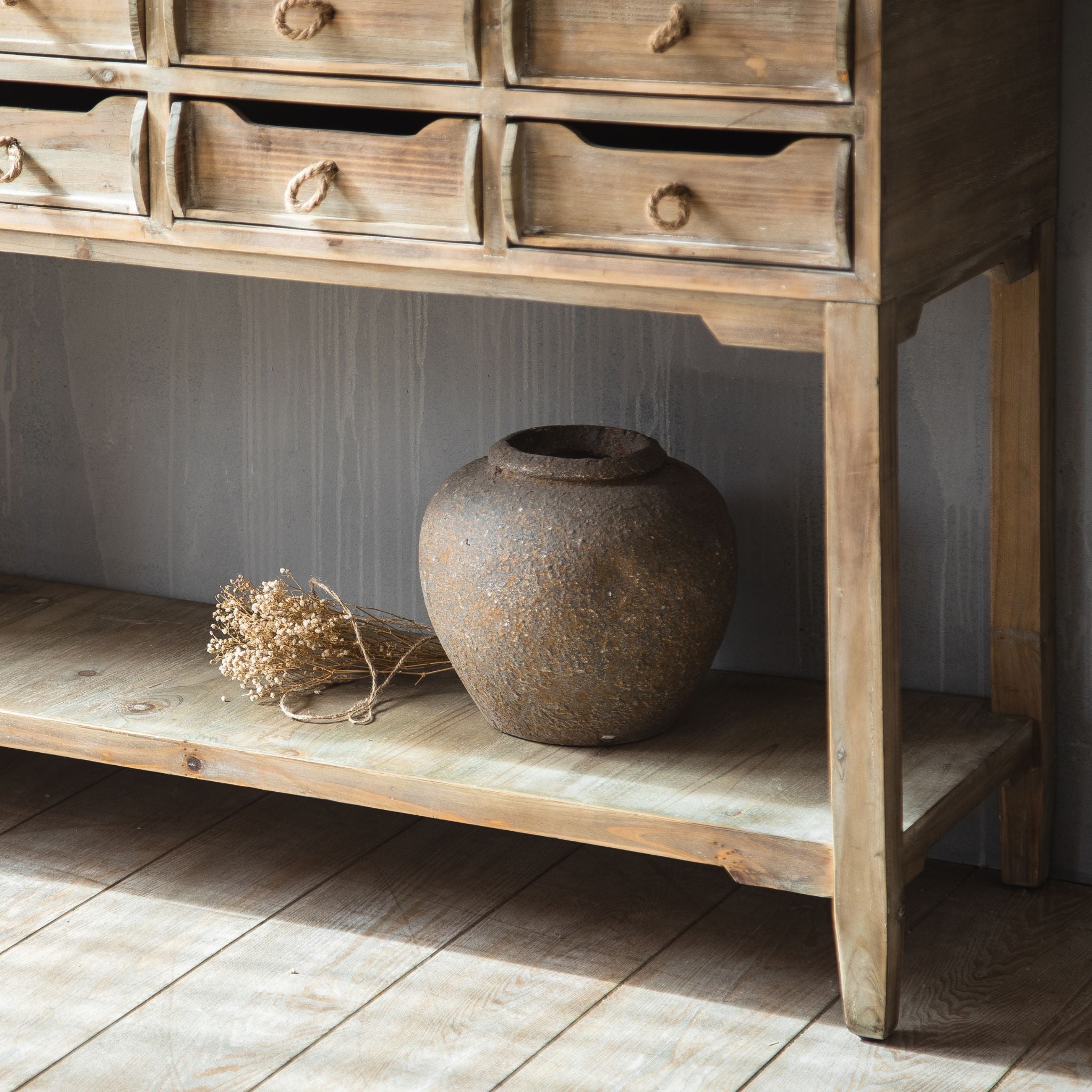 Ada console lower shelf styled with a rustic pot and dried flowers