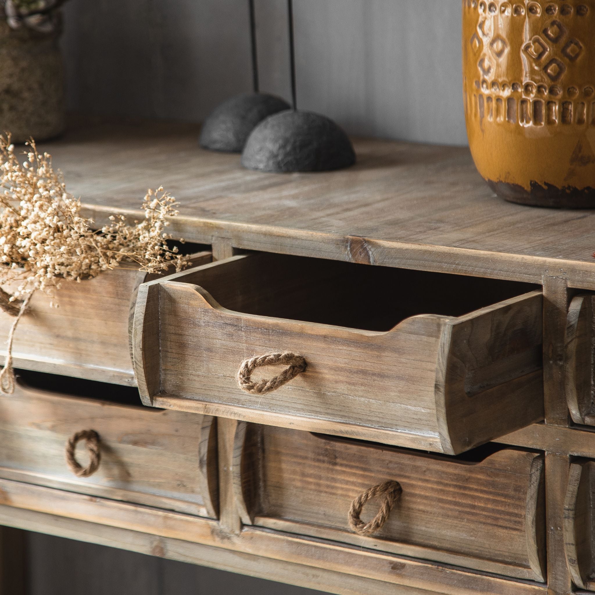 Ada eight drawer console table styled against a grey wall with vases and wall art