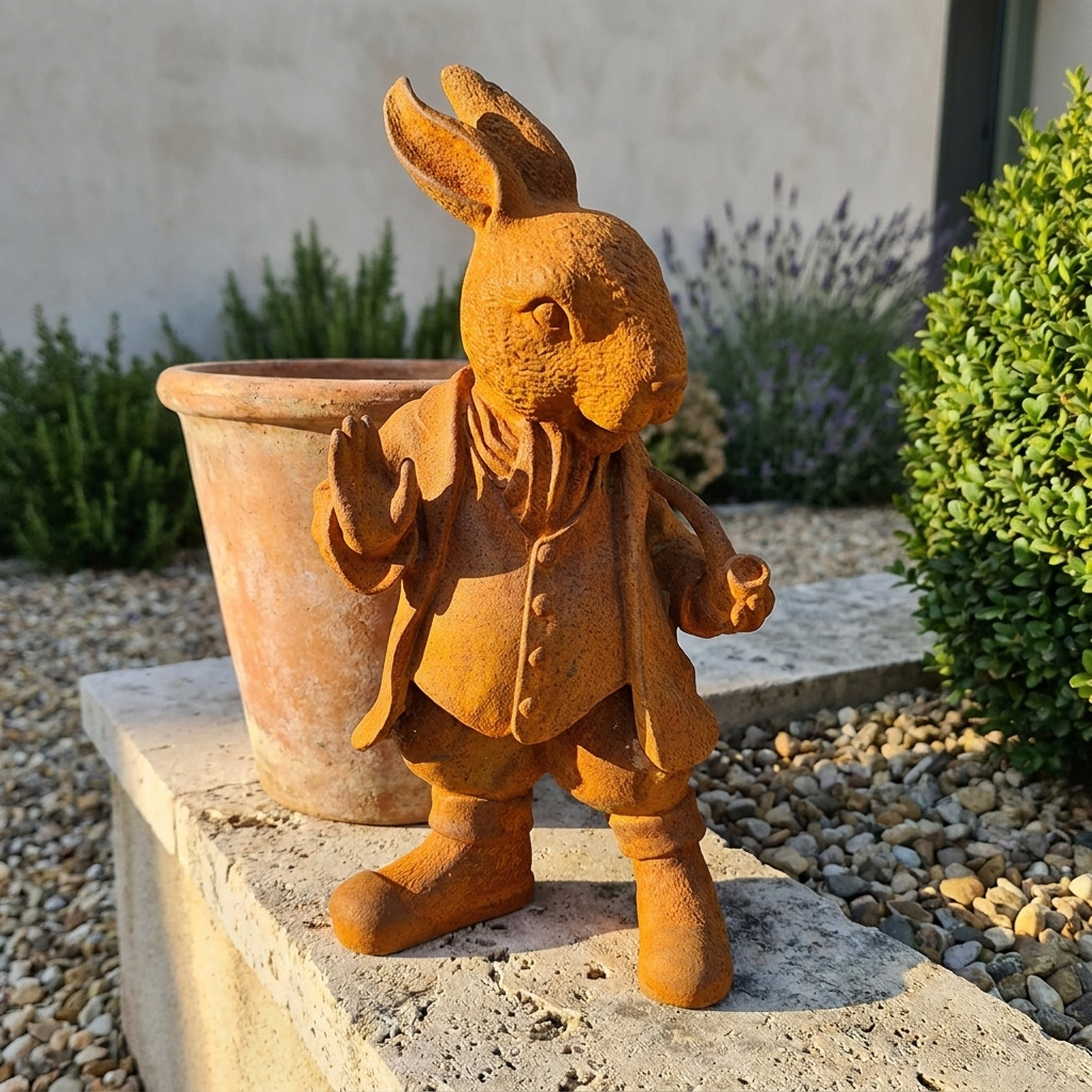 Mayor Cottontail rust cast iron rabbit statue in a frock coat with a raised paw, on a travertine ledge beside a terracotta pot