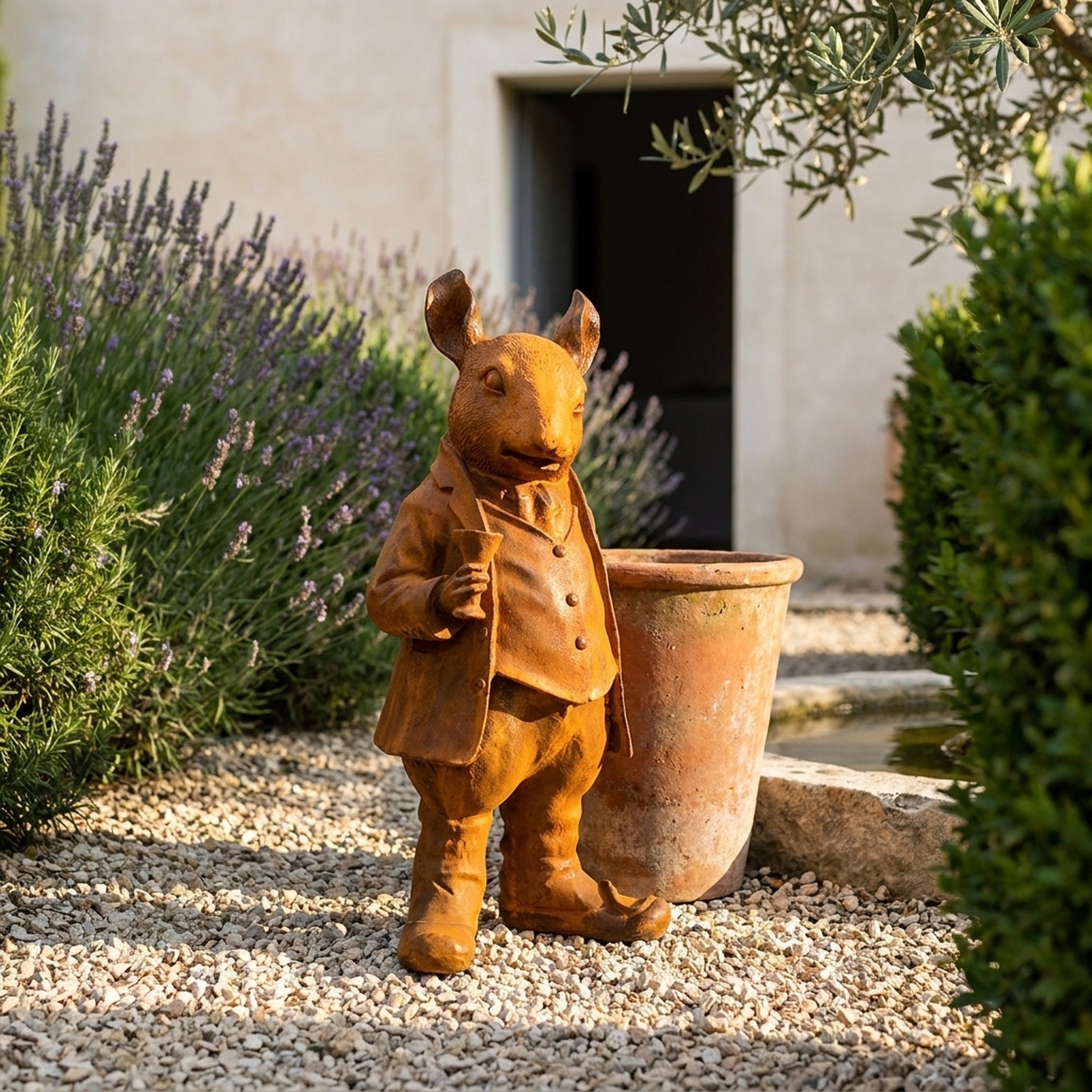 Monsieur Ratsworth large rust cast iron rat statue in a frock coat raising a goblet, on gravel beside a terracotta pot
