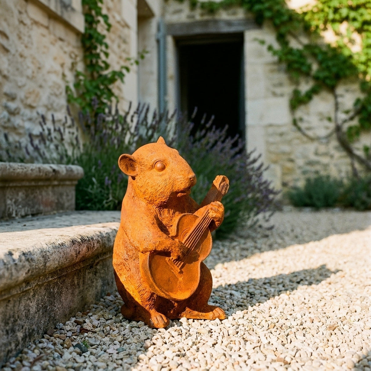 Chester rust cast iron dormouse statue playing a guitar, on gravel