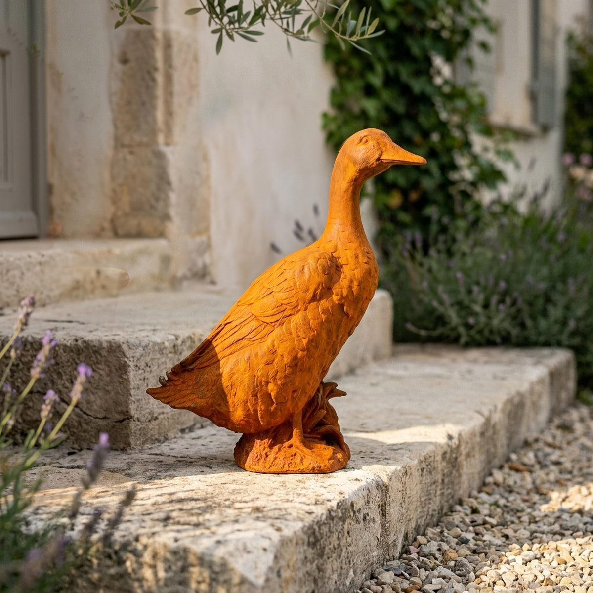 Goosey Gander rust cast iron duck statue on a rock base, standing on gravel