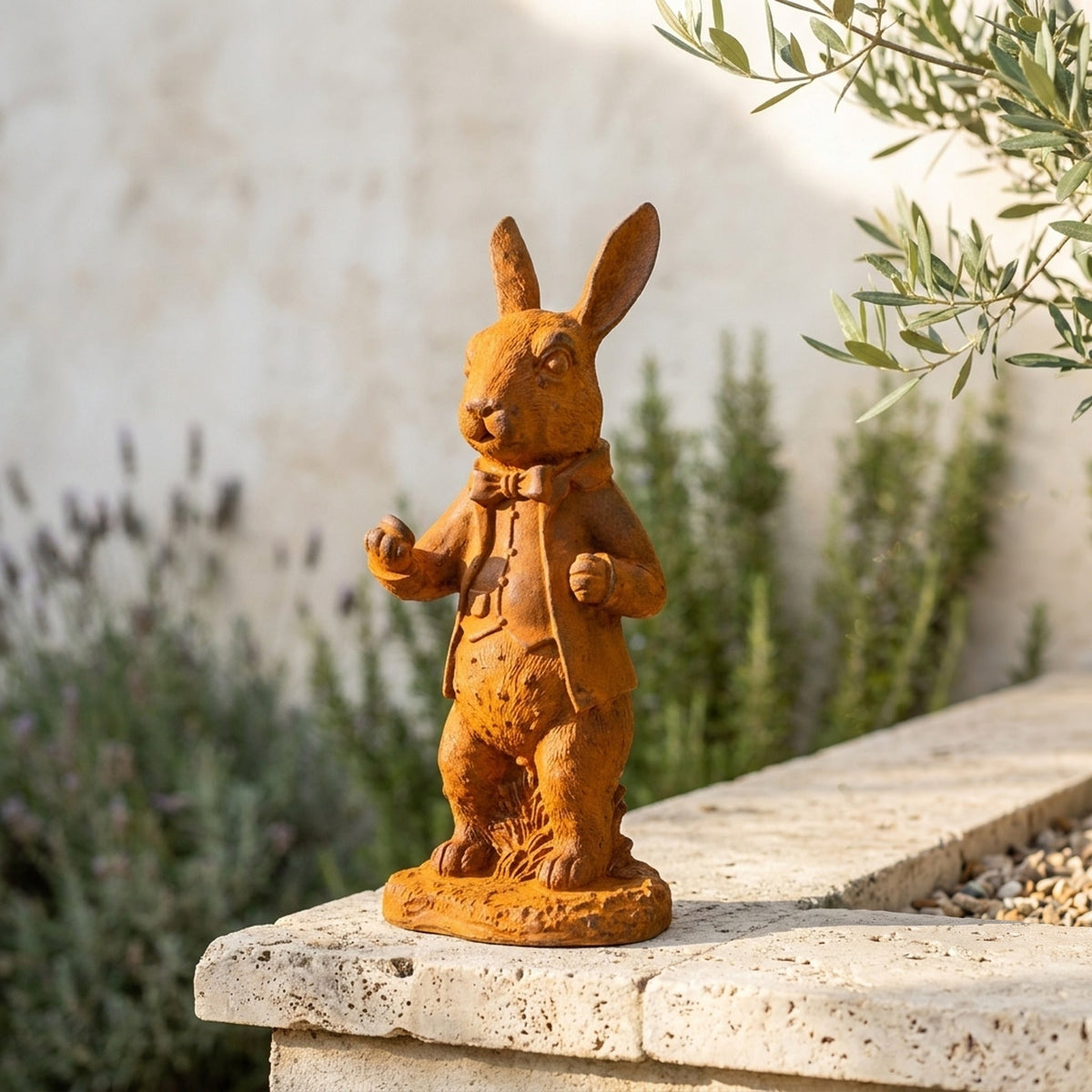 Doctor Bramble rust cast iron rabbit statue in a frock coat on a travertine garden wall with lavender