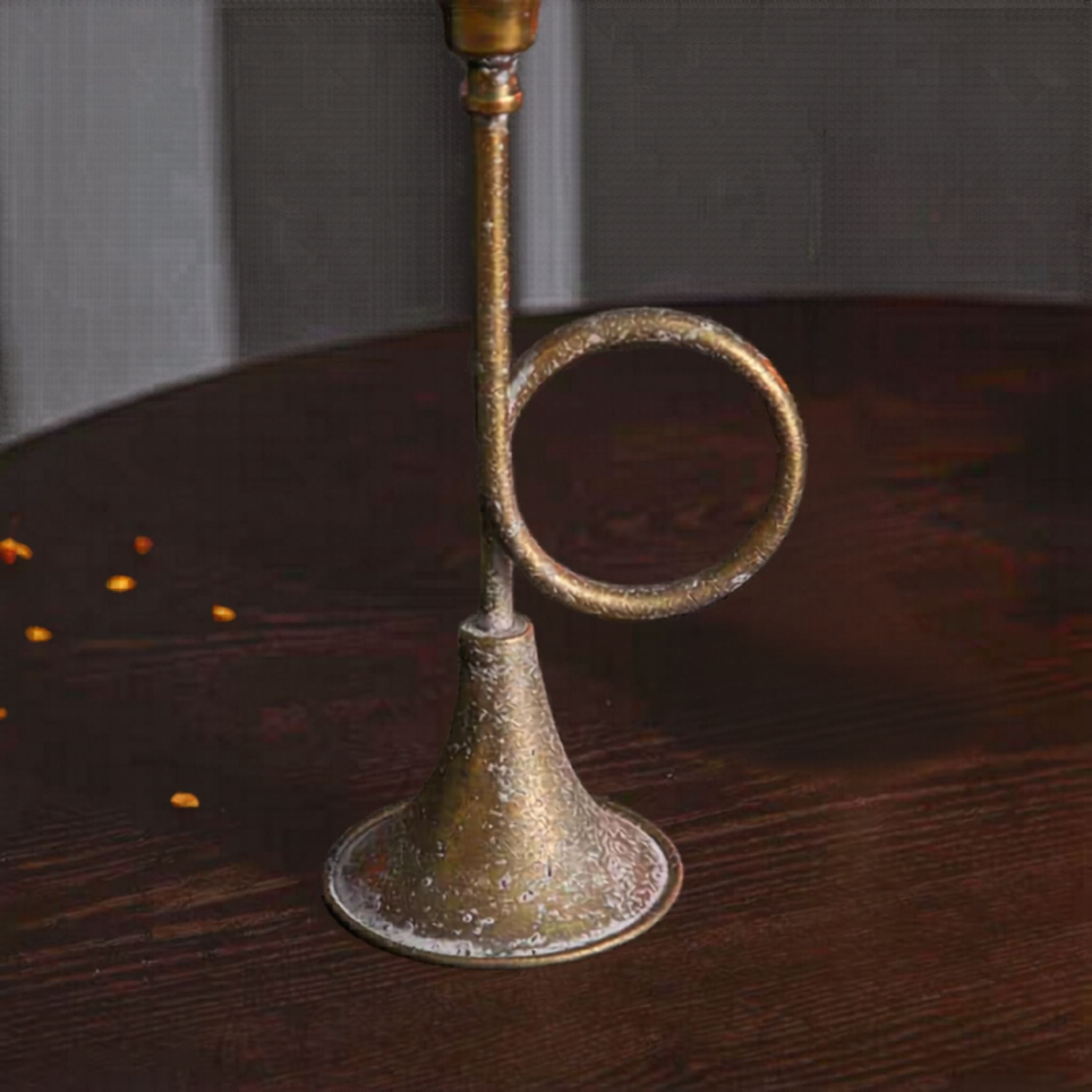 Close detail of the flared foot and coiled loop, aged metal with mottled antique gold.