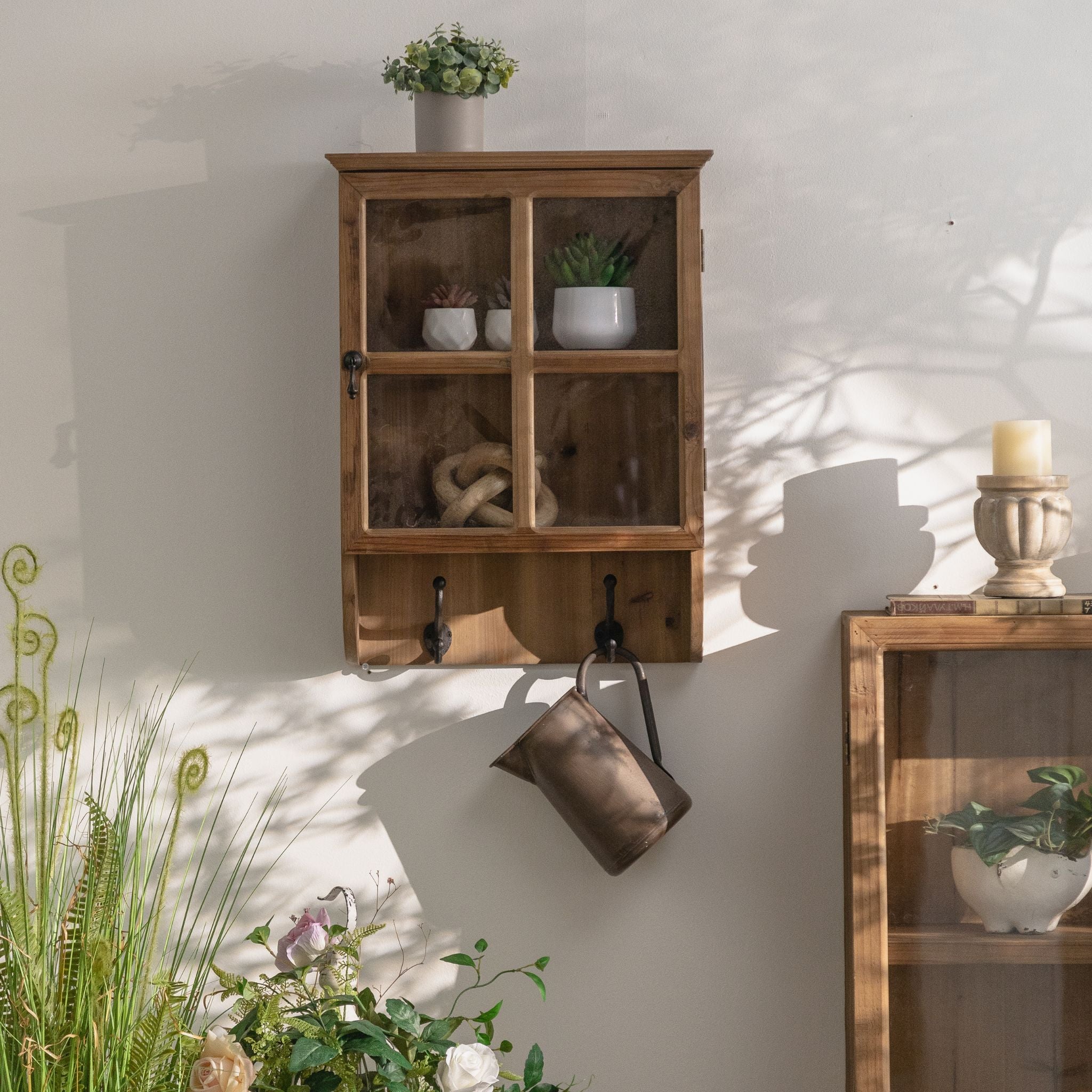 Alain glazed pine wall cabinet with a four-pane door and two cast-iron hooks below. Hero.