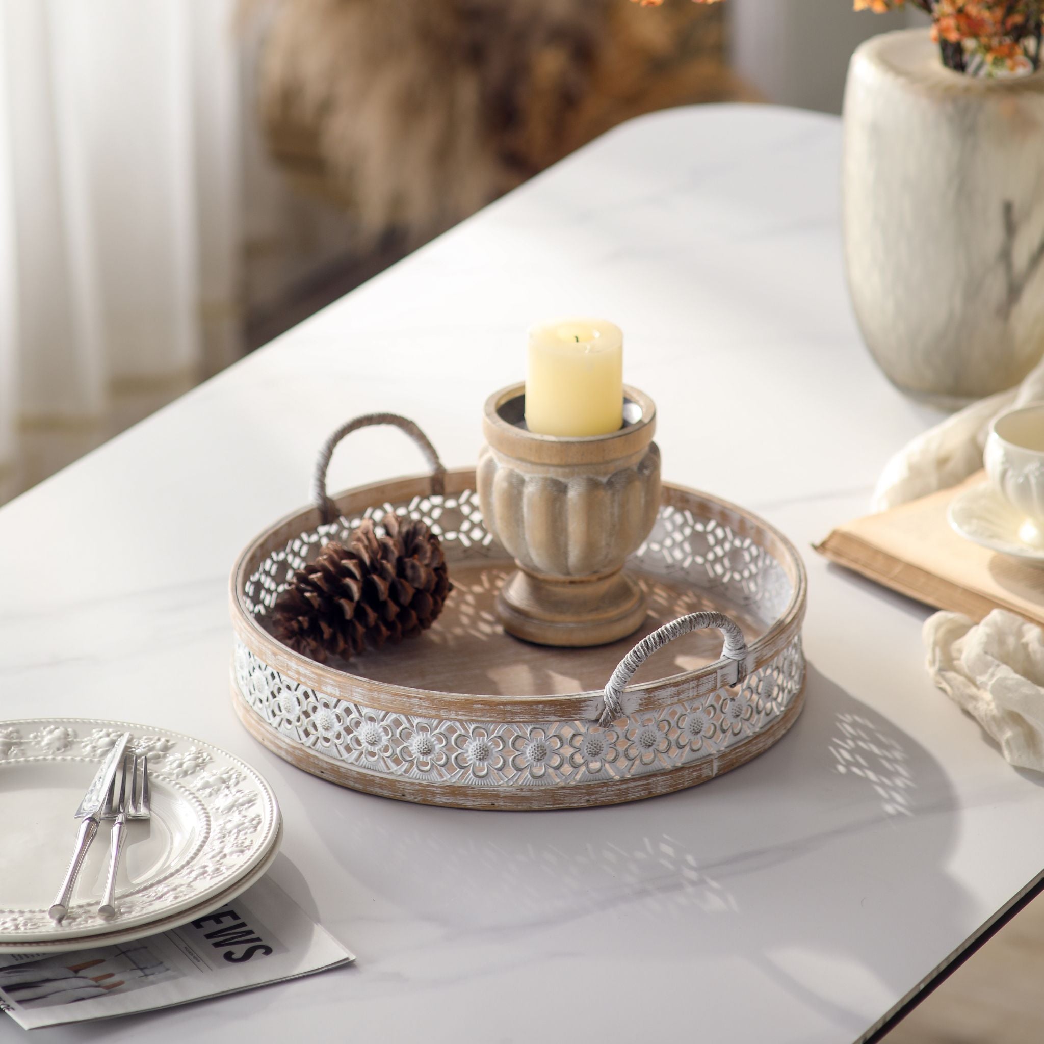 Single Alexandrine round tray holding a candle and pinecone, whitewashed wood base with a white floral metal band