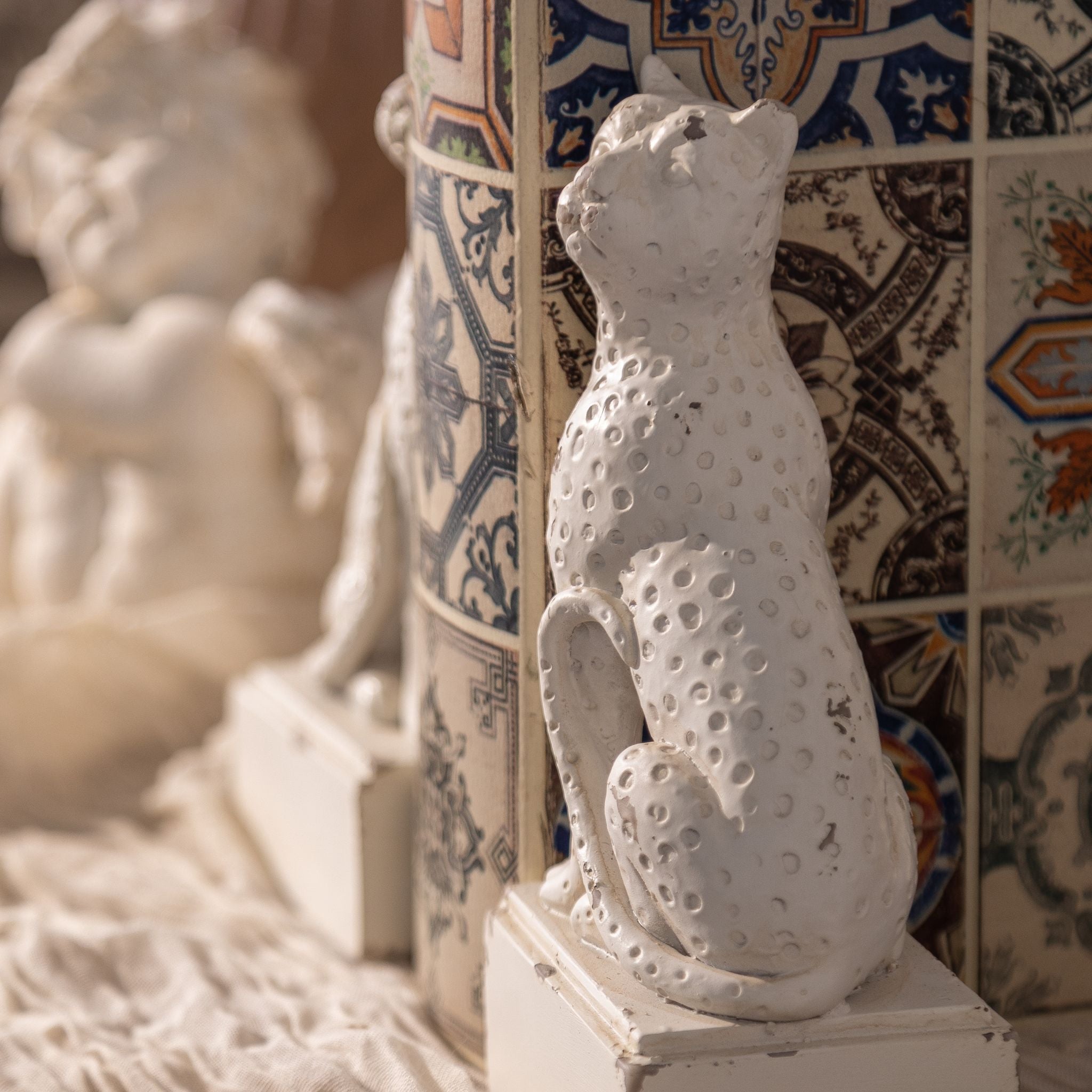 Rear view of an Amandine leopard bookend showing the curled tail and distressed antique white finish