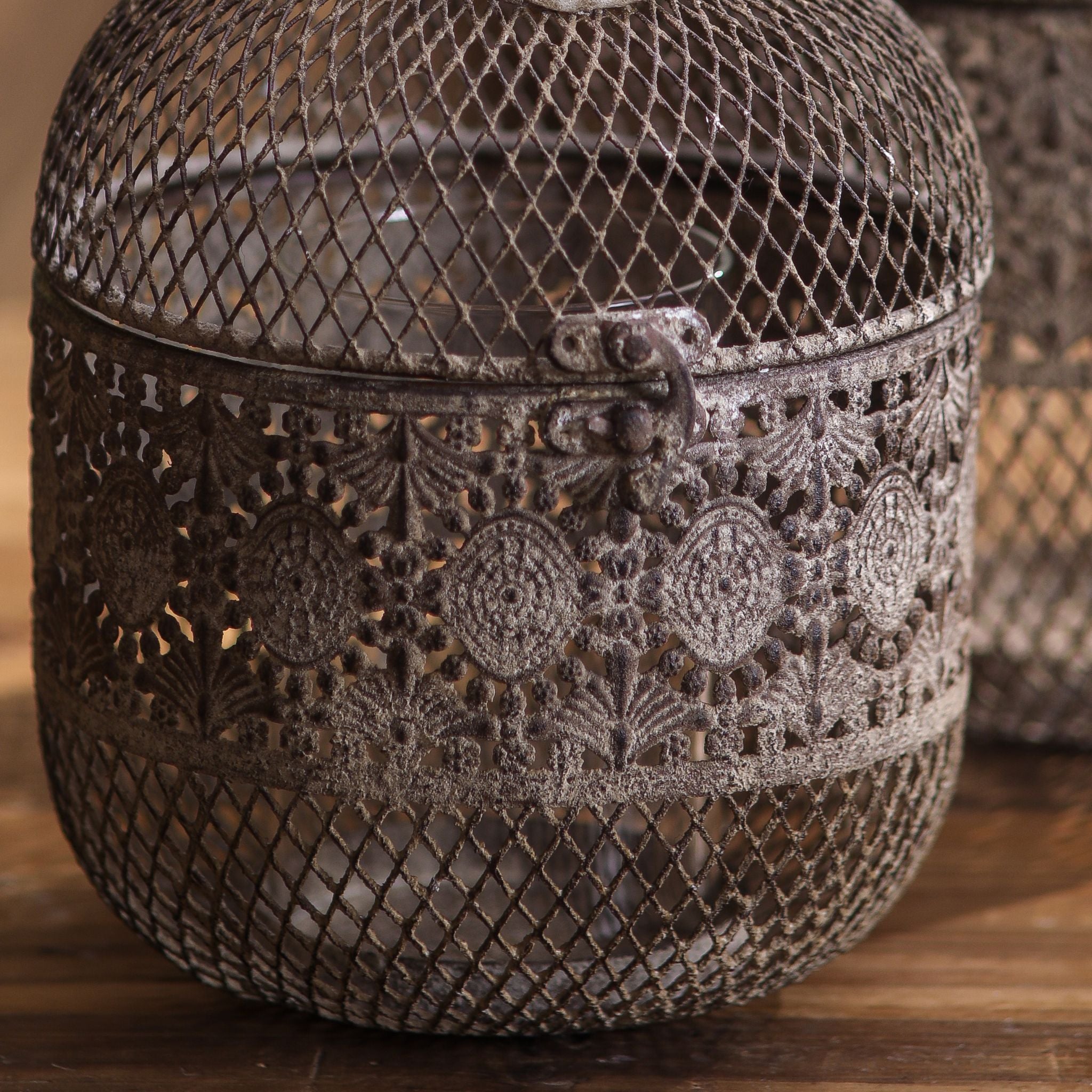 Close-up of the diamond mesh body and pierced lace band on the aged metal lantern with its hinged latch