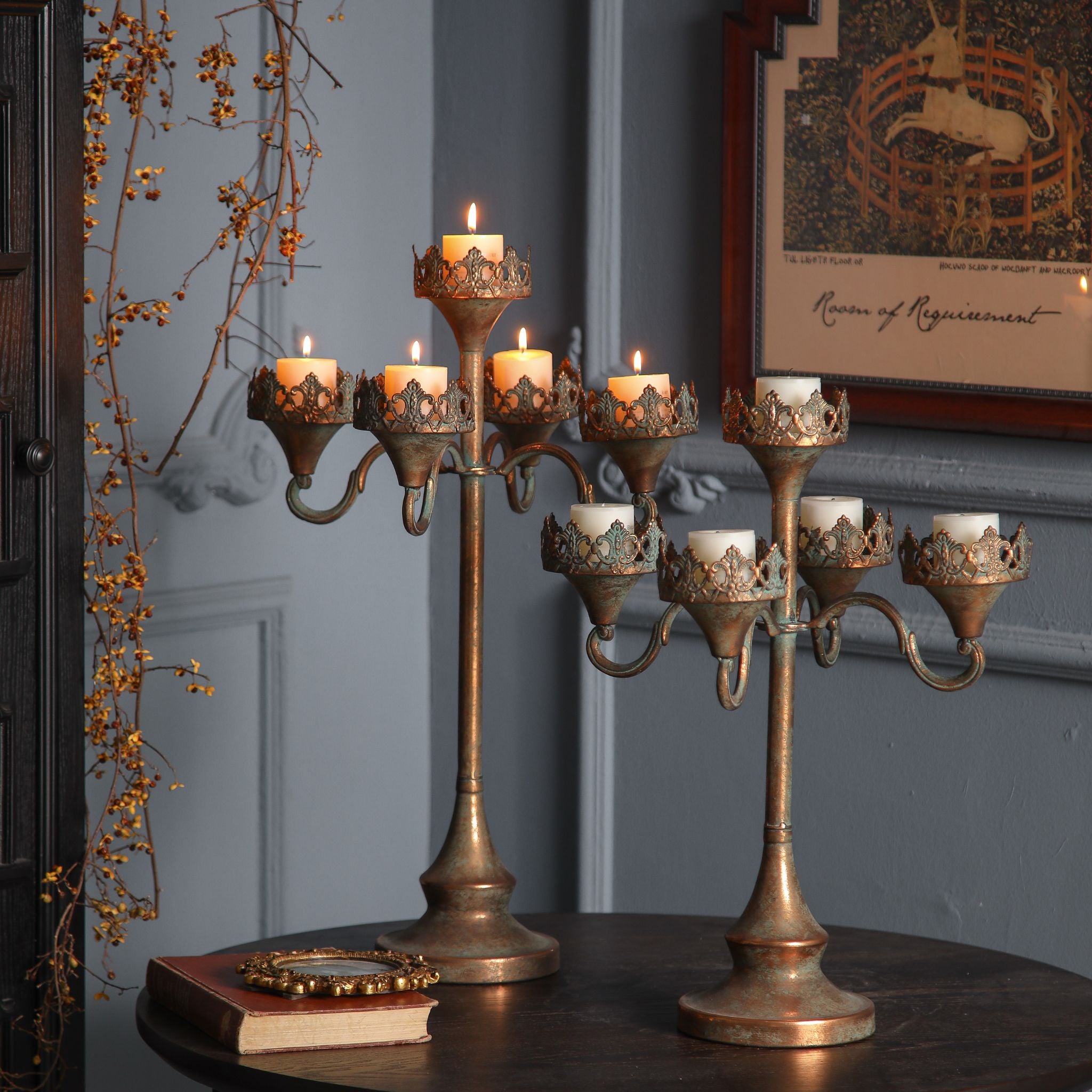 Corrine antique gold five-light candelabra, unlit cream pillar candles, showing the stepped arms and crown collars.