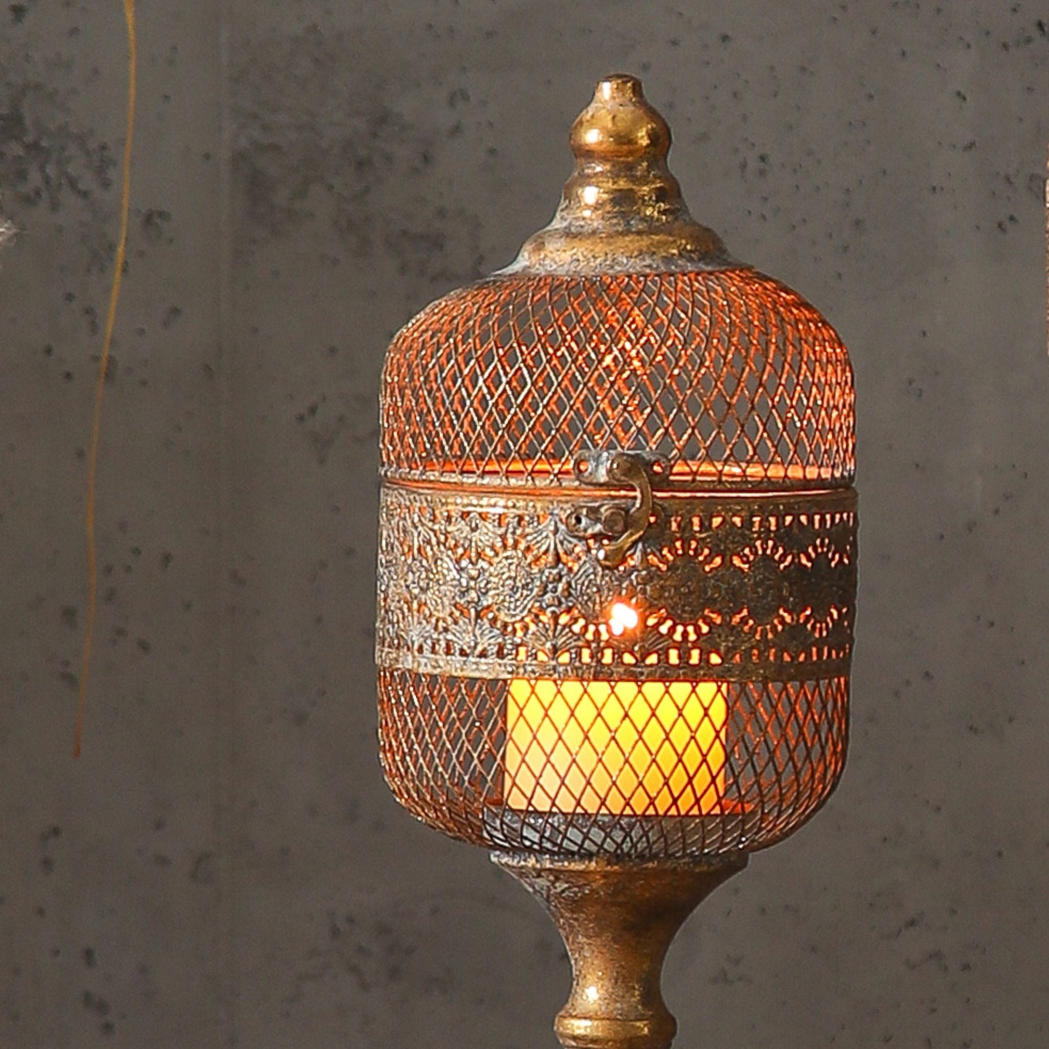 Close detail of the Astrid lantern head, diamond mesh dome, embossed openwork band, ring latch and the glass candle cup lit inside.