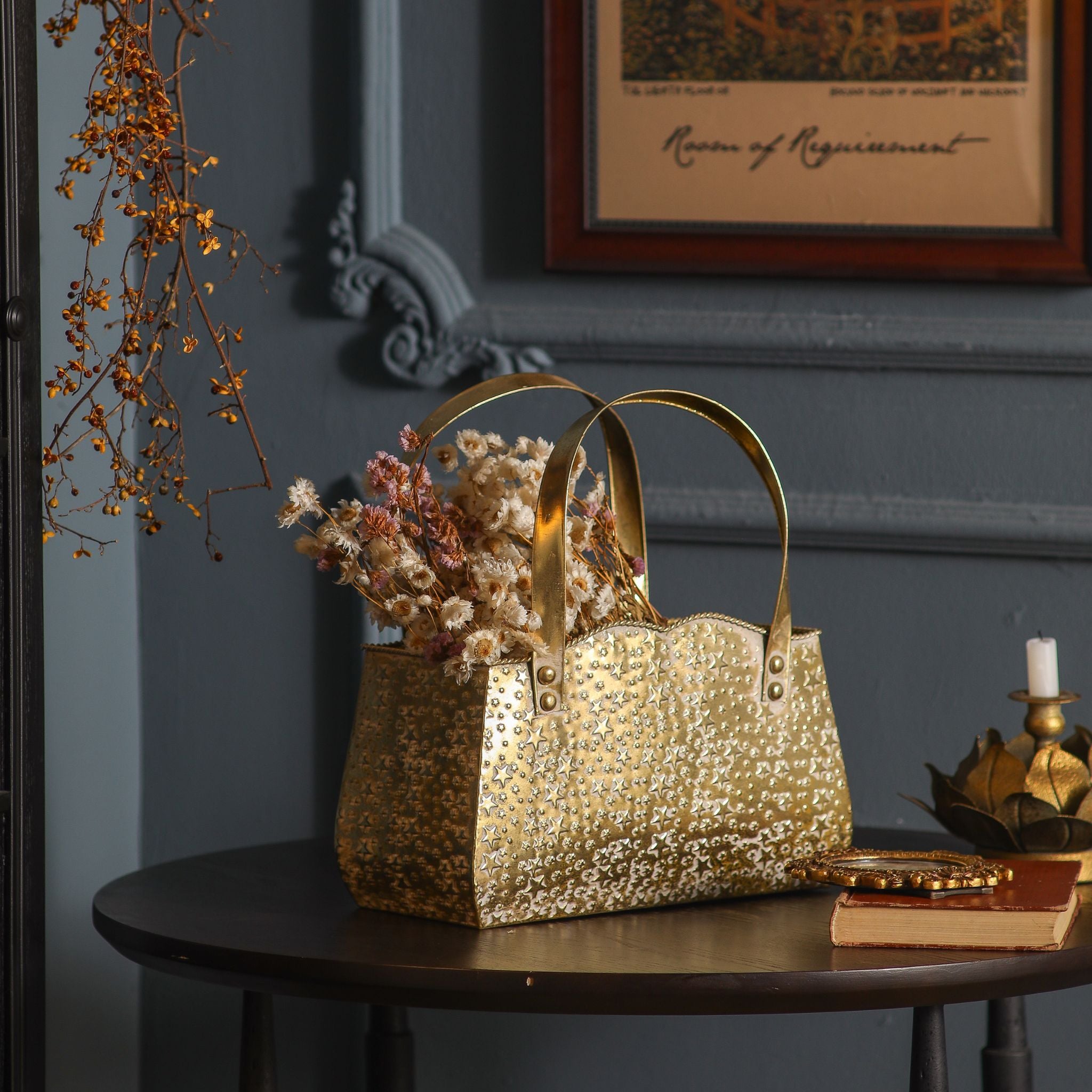 Antique gold star-embossed handbag planter holding dried flowers on a dark side table