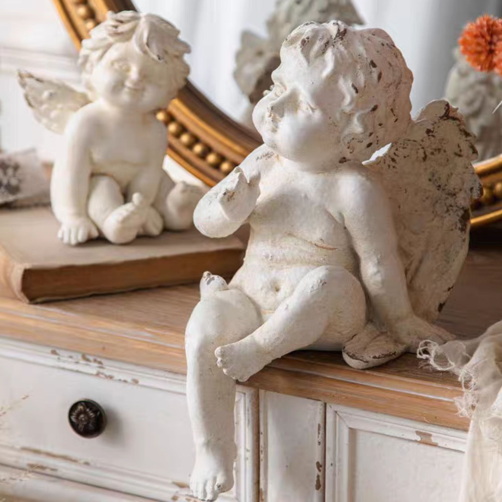 Bastien sitting cherub on the left with the larger Maxime seated cherub on the right, styled on a layered linen and lace setting