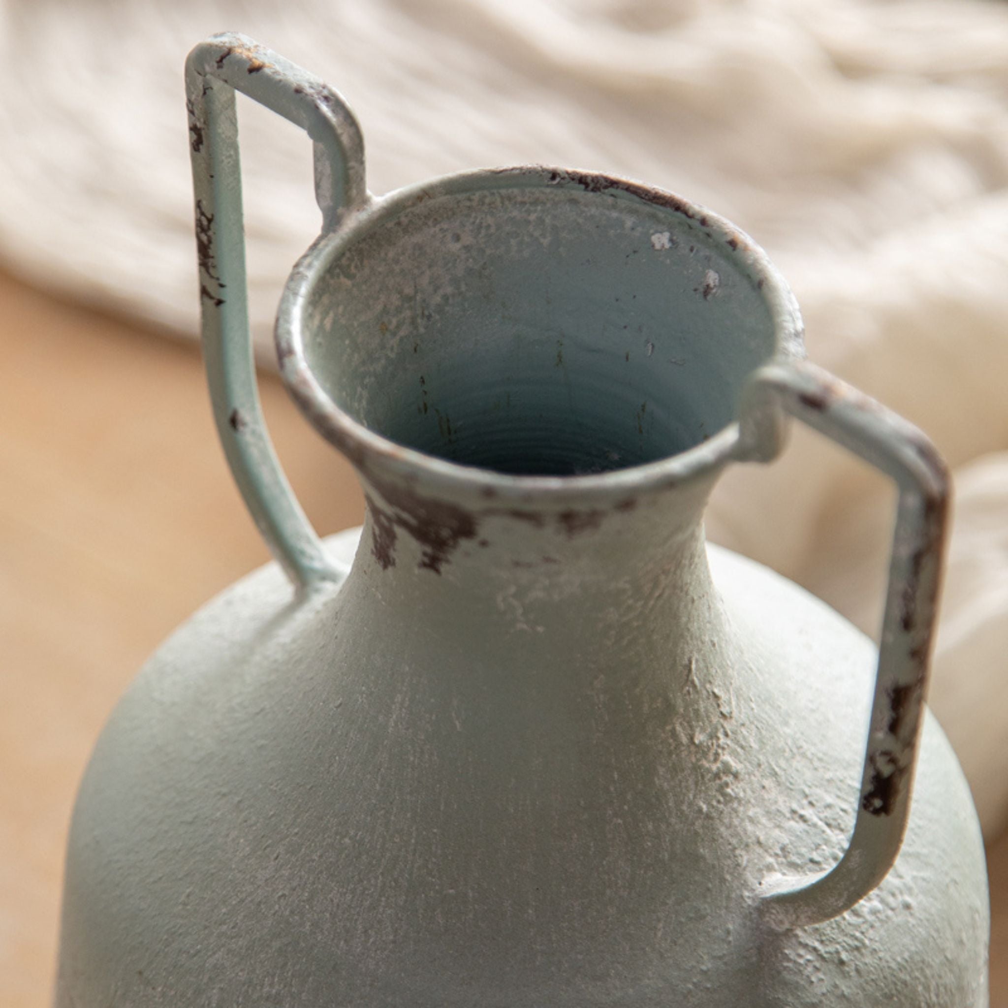 Beau close-up of the flared neck and twin angular handles, paint worn back to dark metal.