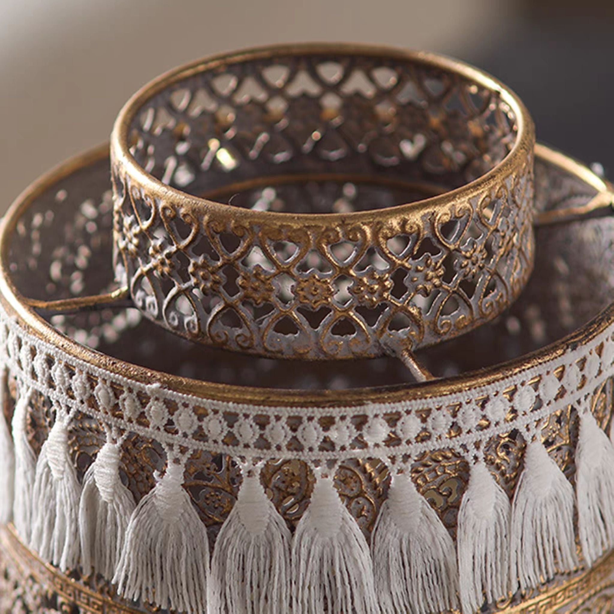 Close-up of the pierced filigree body, inner tealight cup, and white cotton tassel trim.
