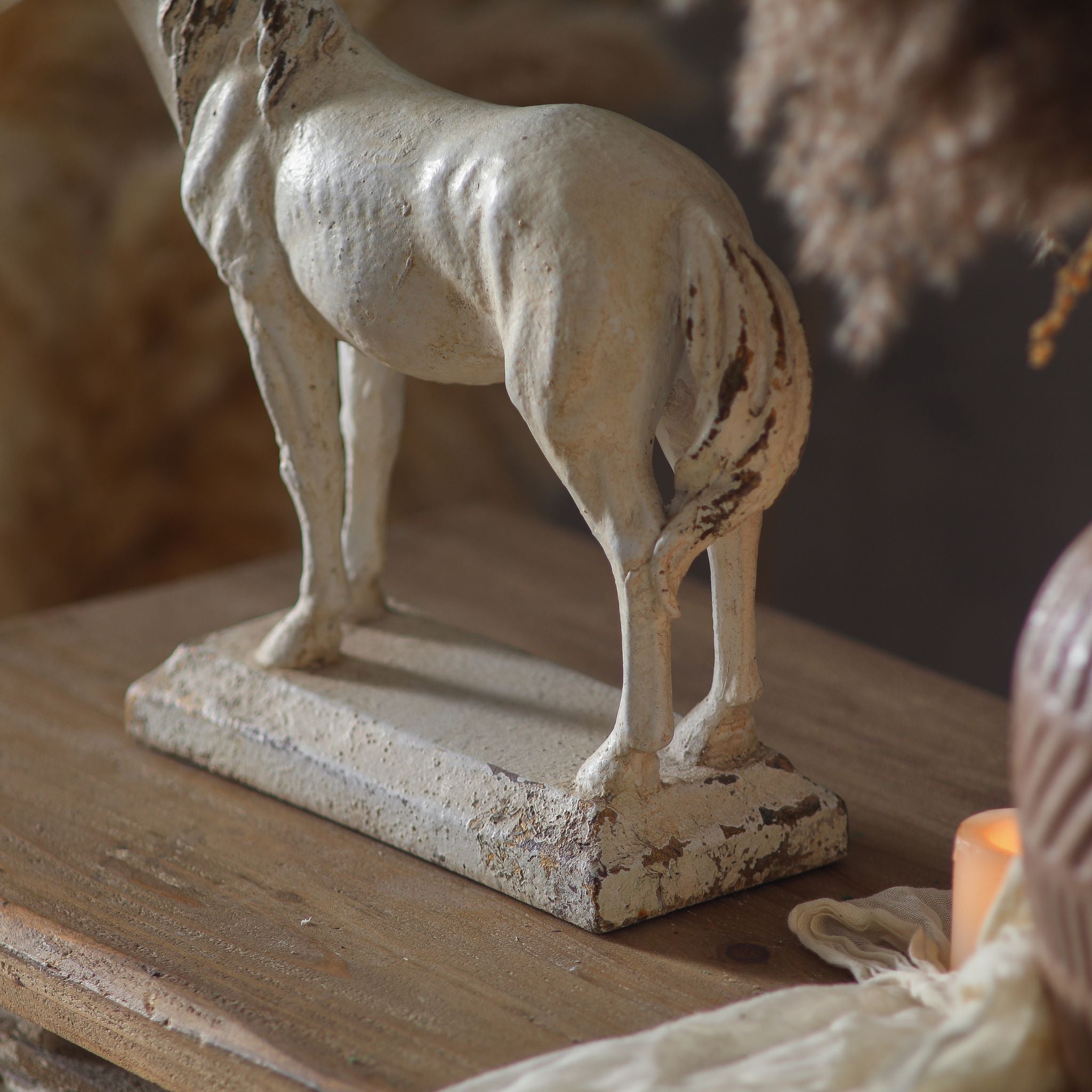 Detail of the Camargue horse sculpture's rear legs and plinth base, showing chippy distressed paintwork and the cast stone finish.