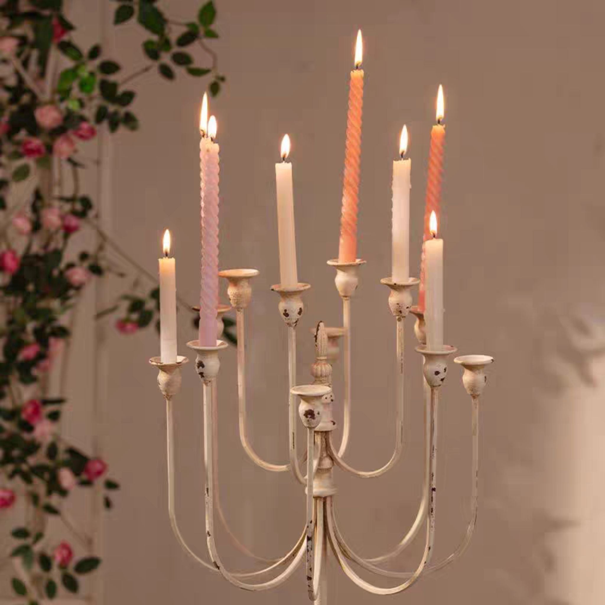 Close view of the two tiers of curved arms and candle cups in distressed cream holding tapers.