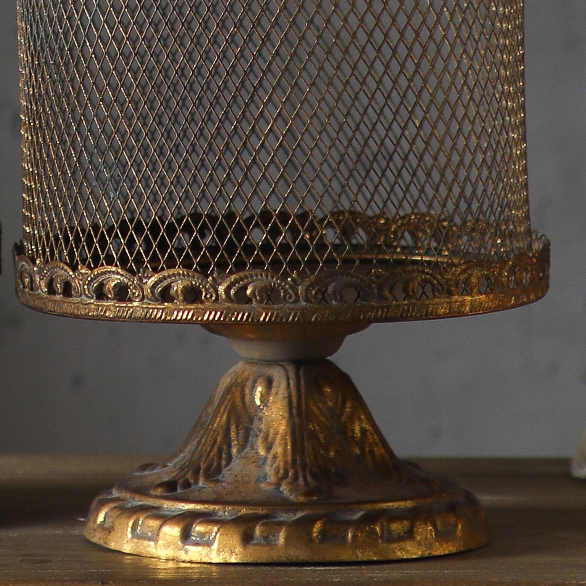 Close-up of the scrolled pierced rim and turned pedestal foot in antique gold