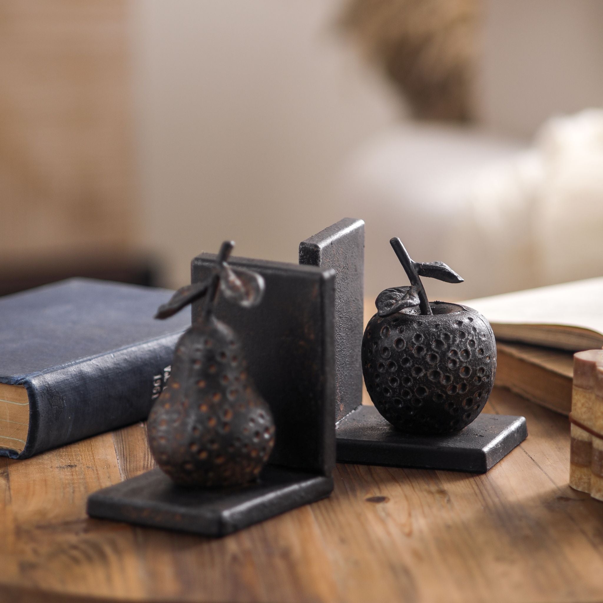 The Poire bookends styled on a wooden table beside an old book, apple in the foreground.
