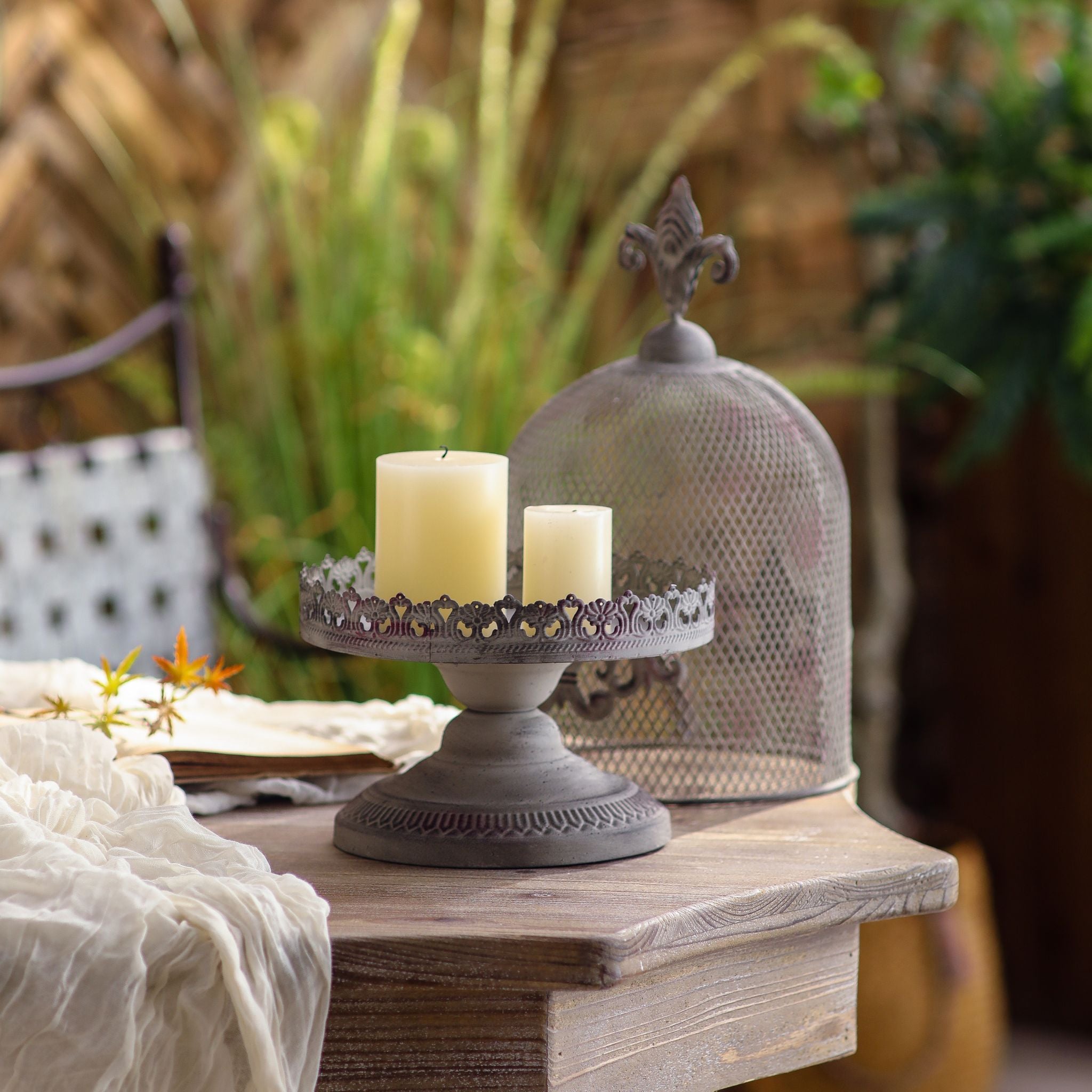 Cécile candle cloche with the dome lifted off, used as a lacework pedestal tray holding two ivory pillar candles on a French Provincial side table.
