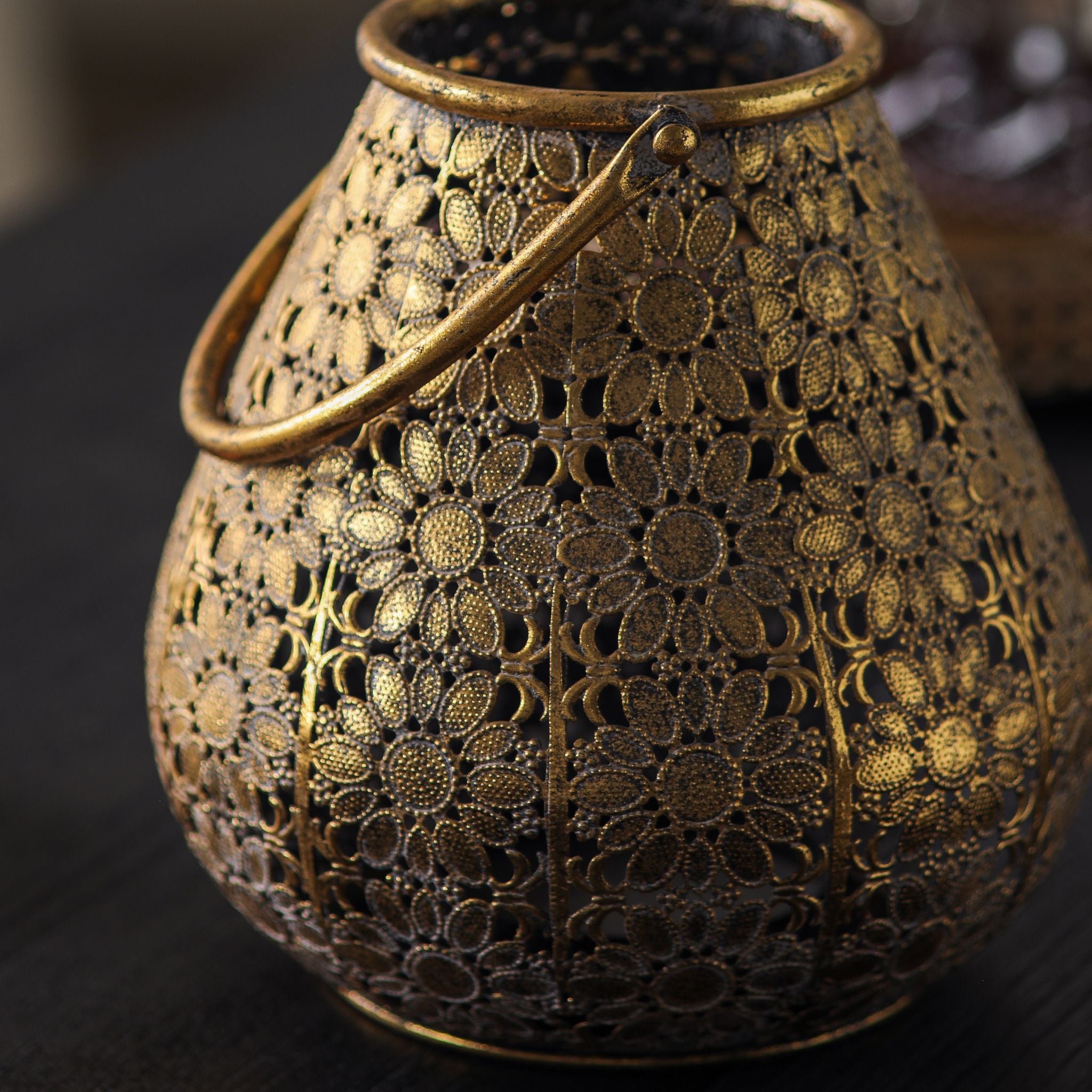 Close-up of the dense floral filigree and antique gold finish worn over a darker base