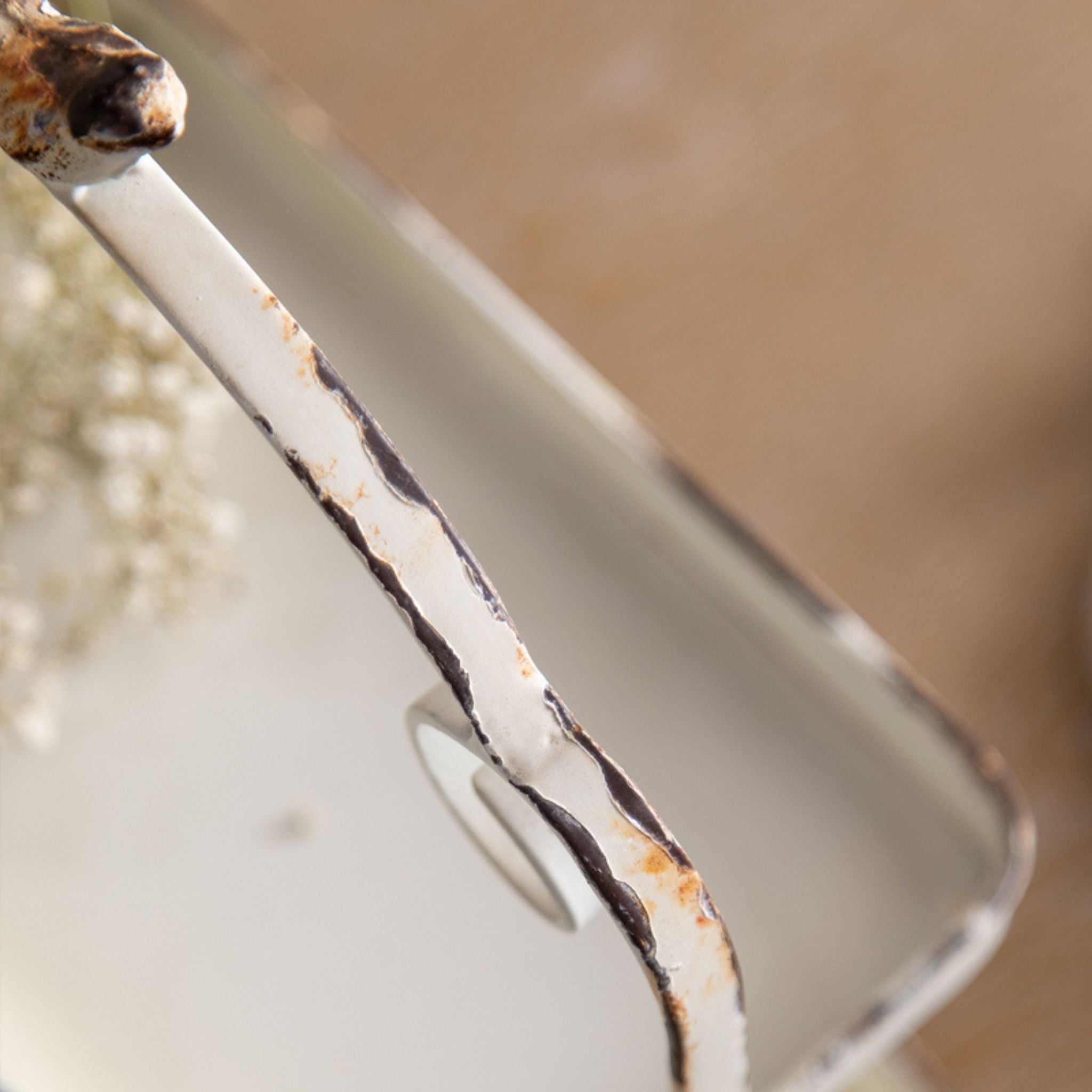 Close view of the chipped, worn white finish on the metal frame