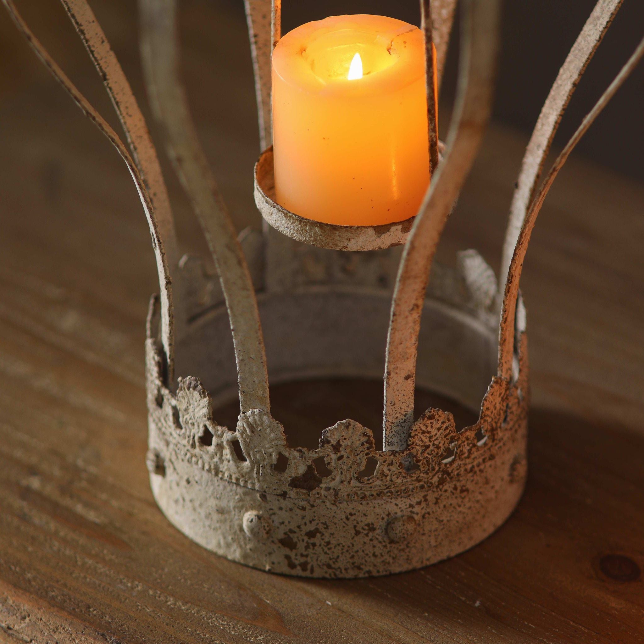 Close-up of the pierced crown base and the small candle cradle holding a lit candle