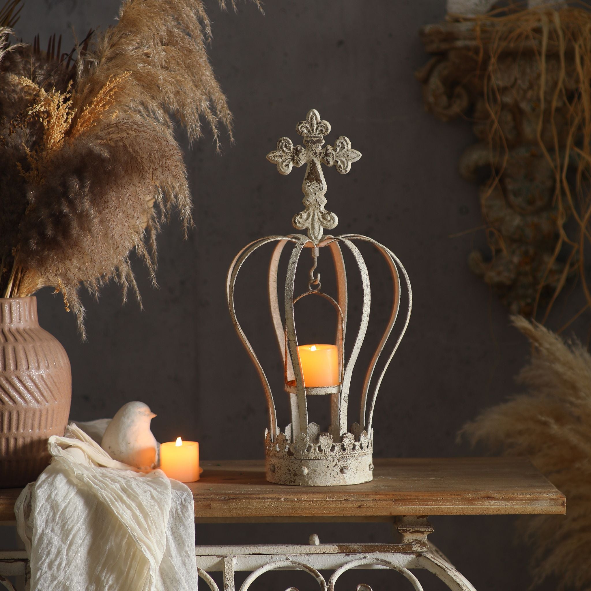 Blanche crown candle holder styled on a console with a lit candle inside, dried grasses behind