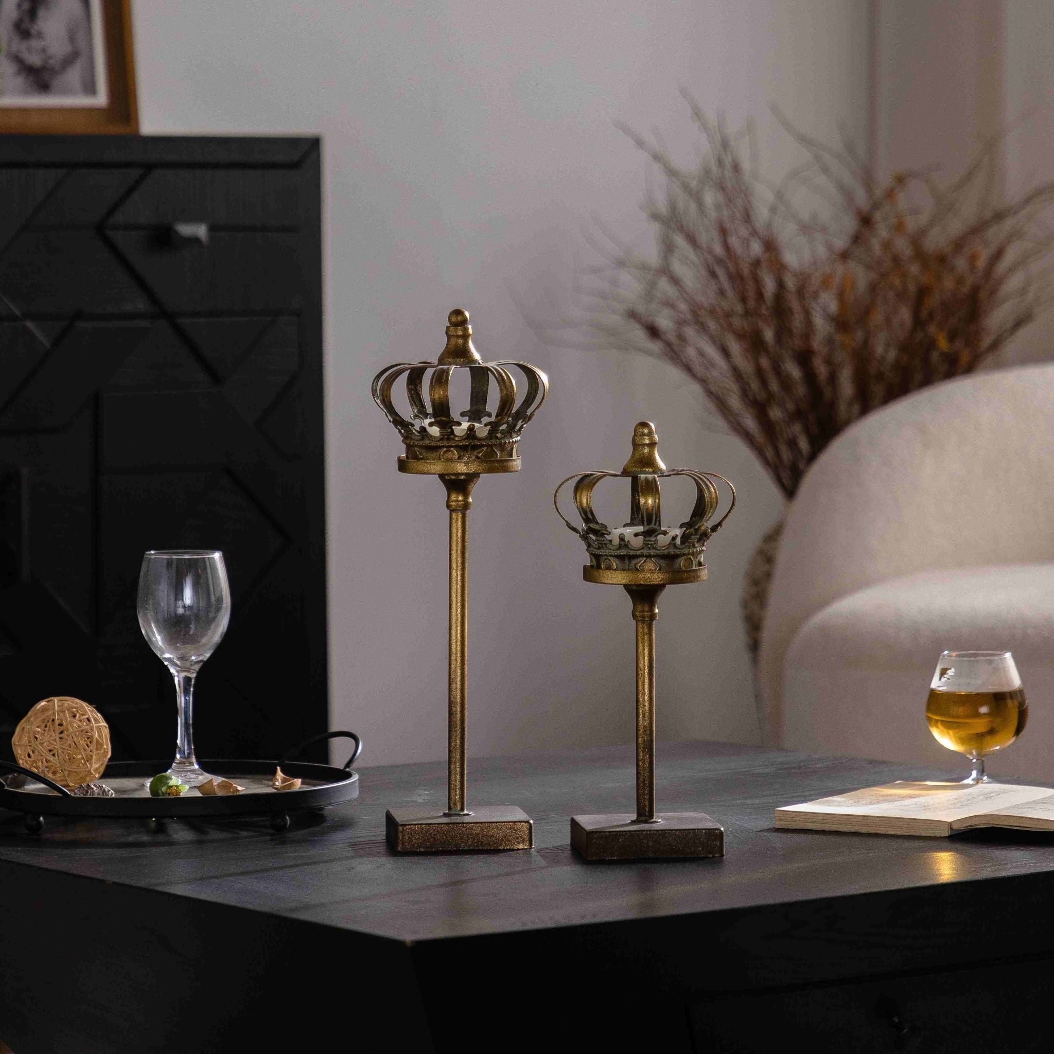 Jade set of two antique gold crown tealight holders on slim stands, two heights, on a dark console.