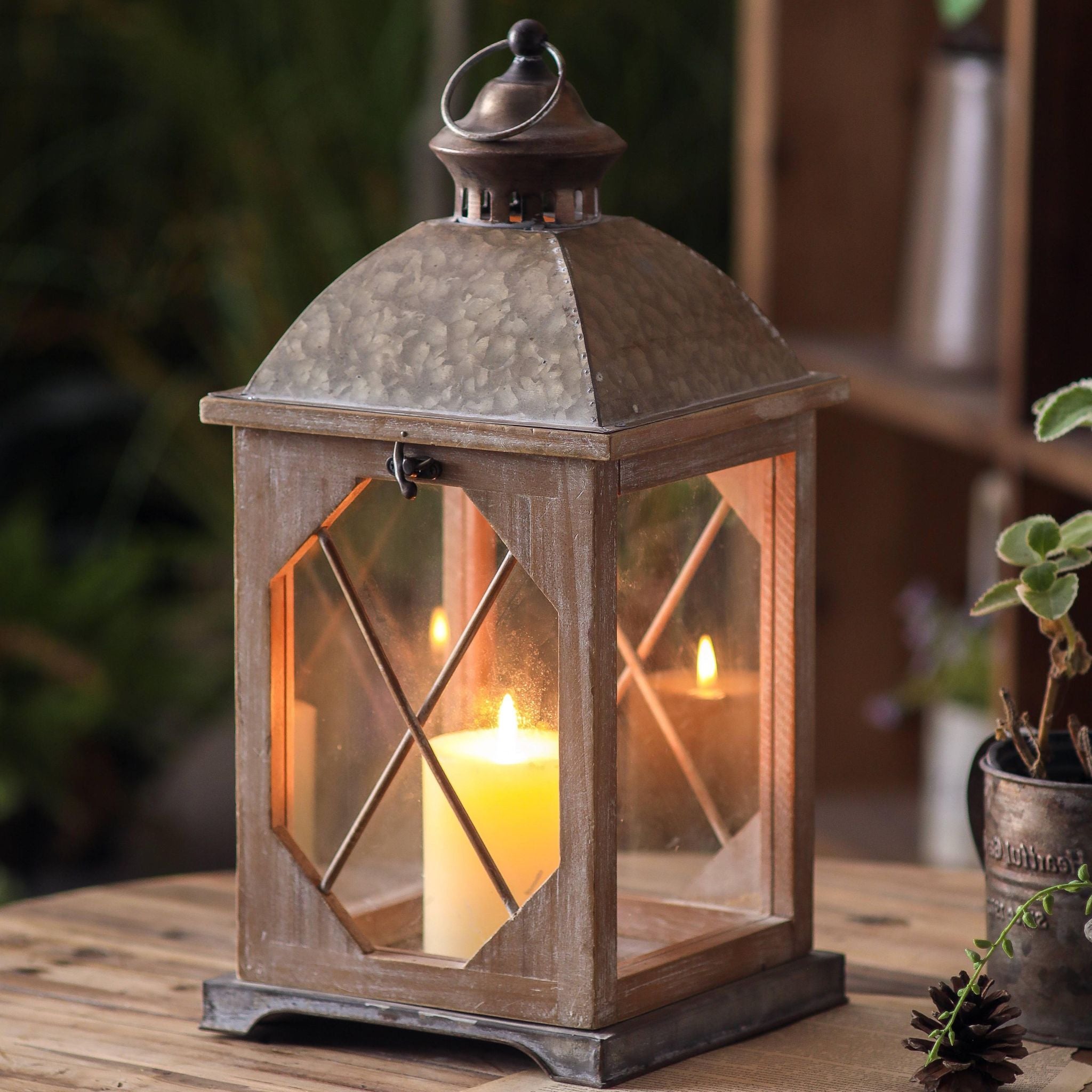Whitewashed wood lantern with galvanised metal top and a glowing pillar candle