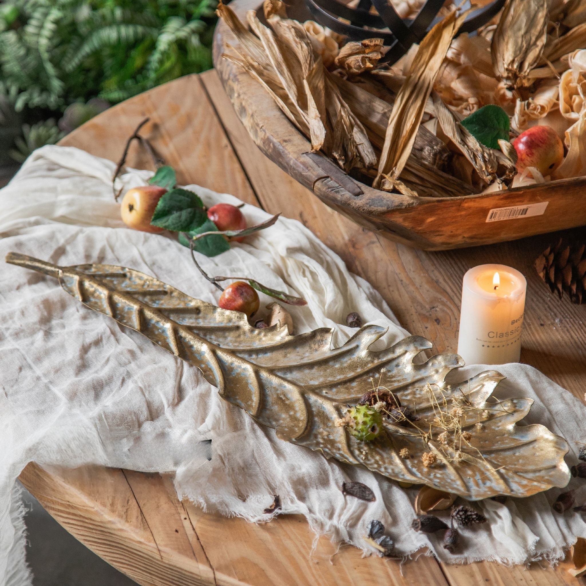Antique gold metal leaf dish styled on a wooden table with a candle