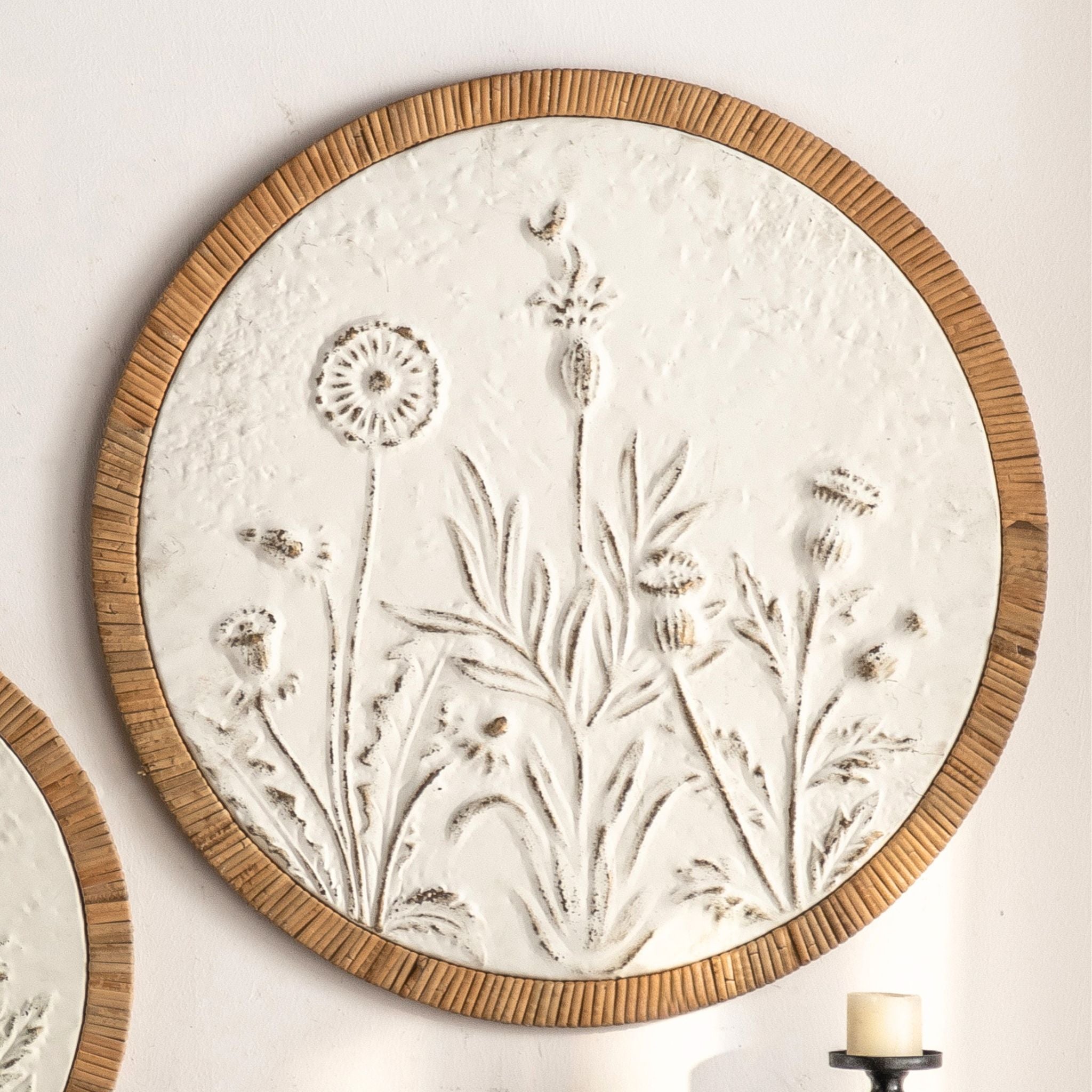 Dumas French Provincial round wall art, embossed meadow of wildflowers in distressed white with a natural rattan frame.