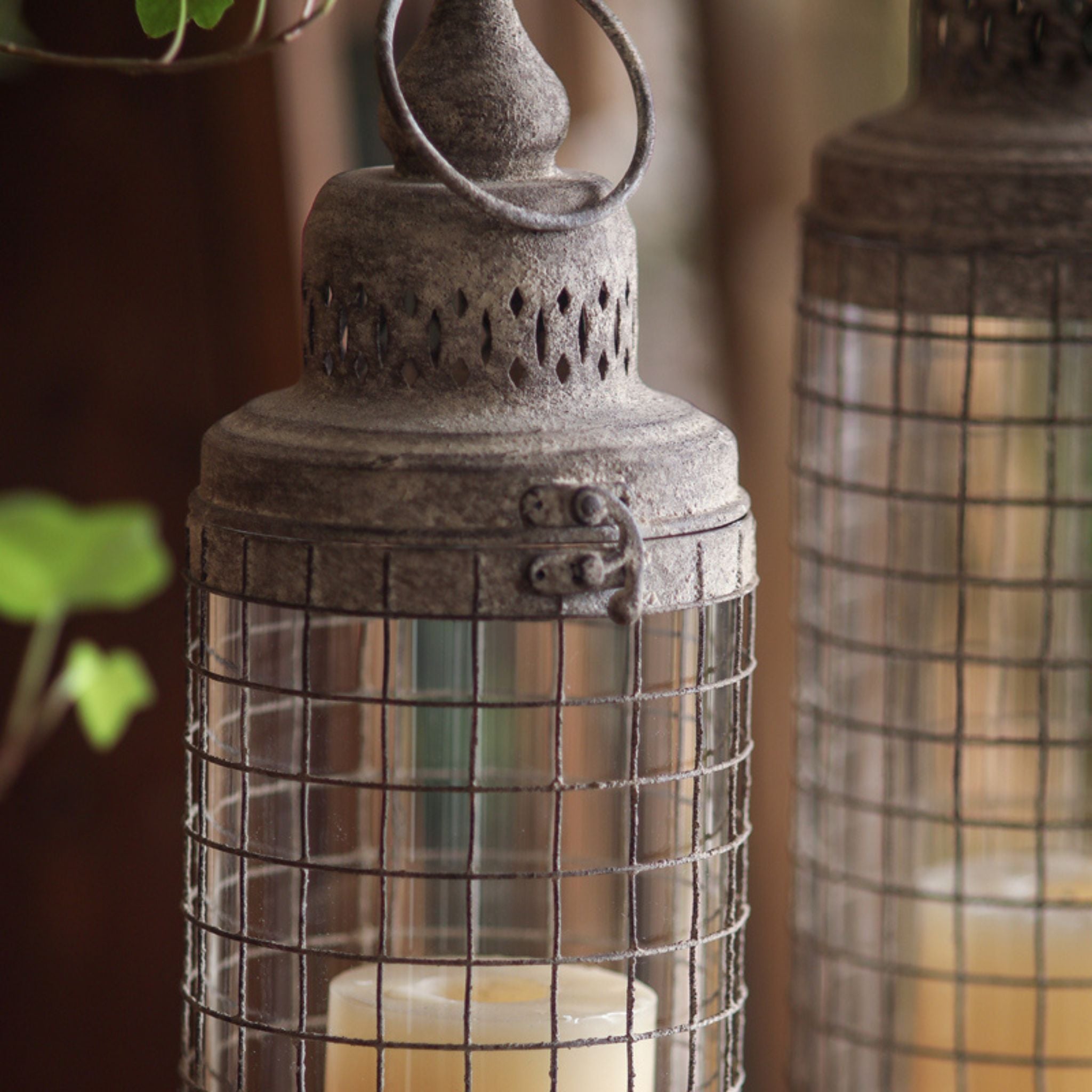Close detail of the Elliott lantern, welded wire grid over the clear glass sleeve with the cream pillar candle inside