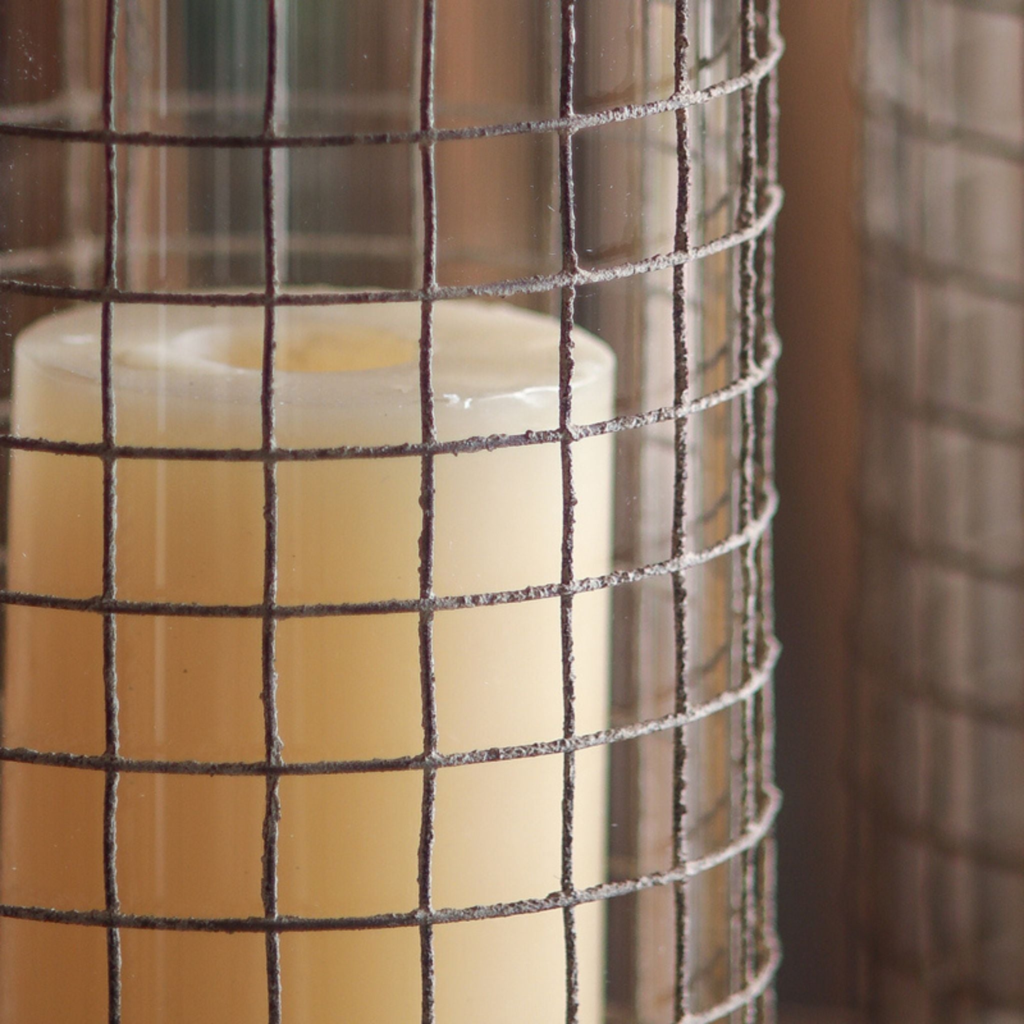 ower detail of the Elliott lantern, lit pillar candle behind glass above the flared weathered grey base.