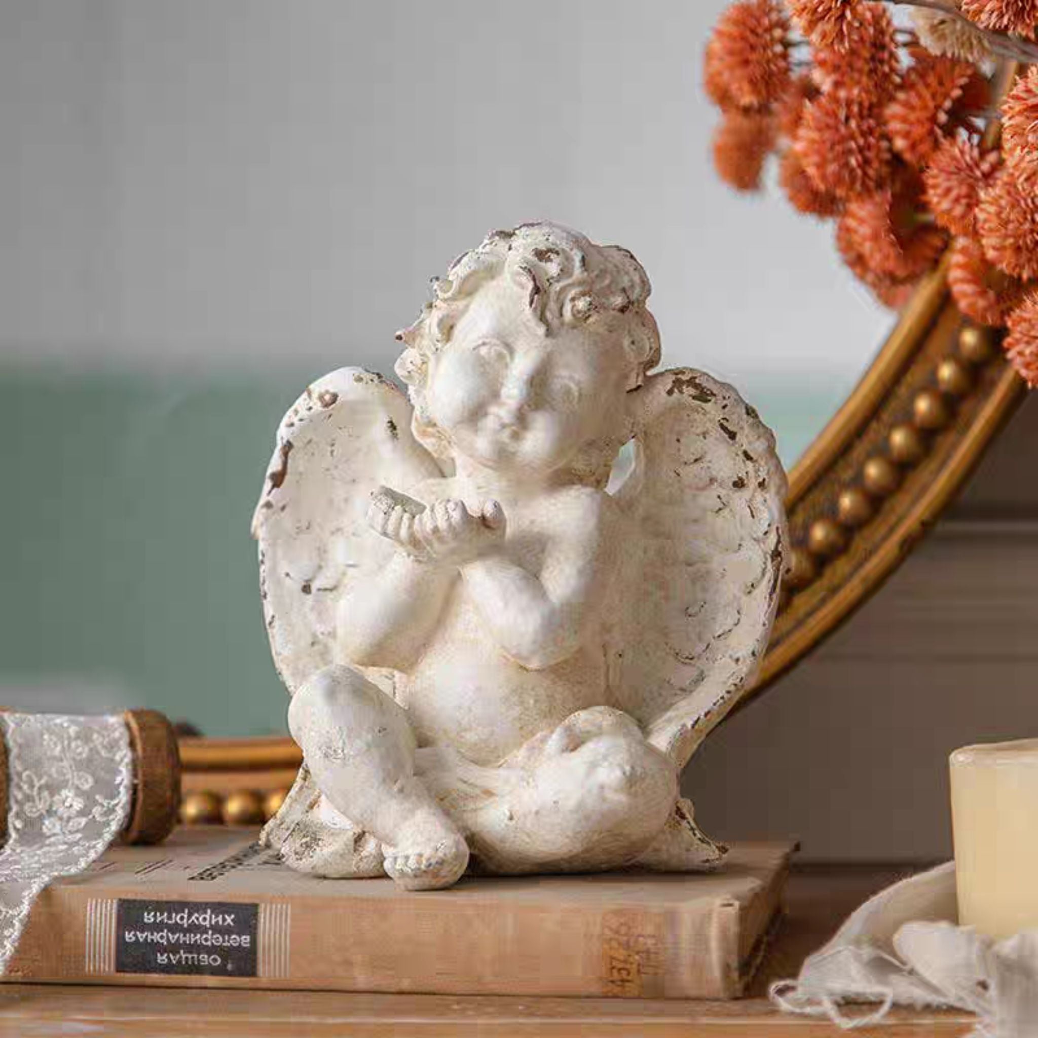 Élodie French Provincial cherub figurine in distressed whitewash, styled with a gilt mirror and dried florals.