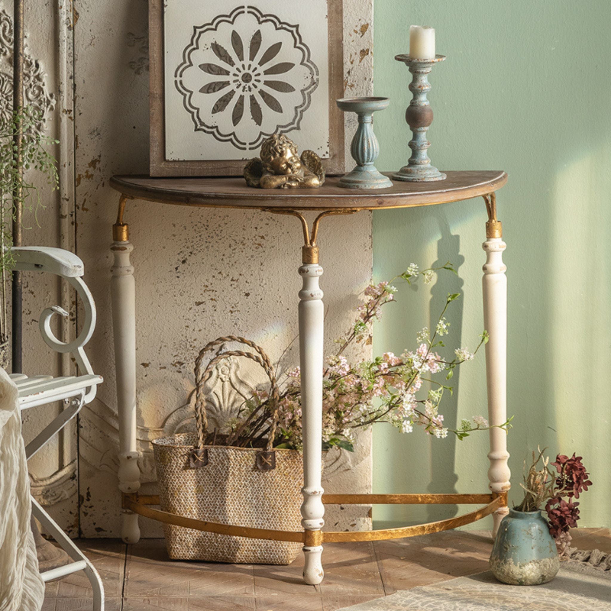 Estelle half moon console table three-quarter angle showing all three turned cream legs and the curved gold-leaf iron stretcher.